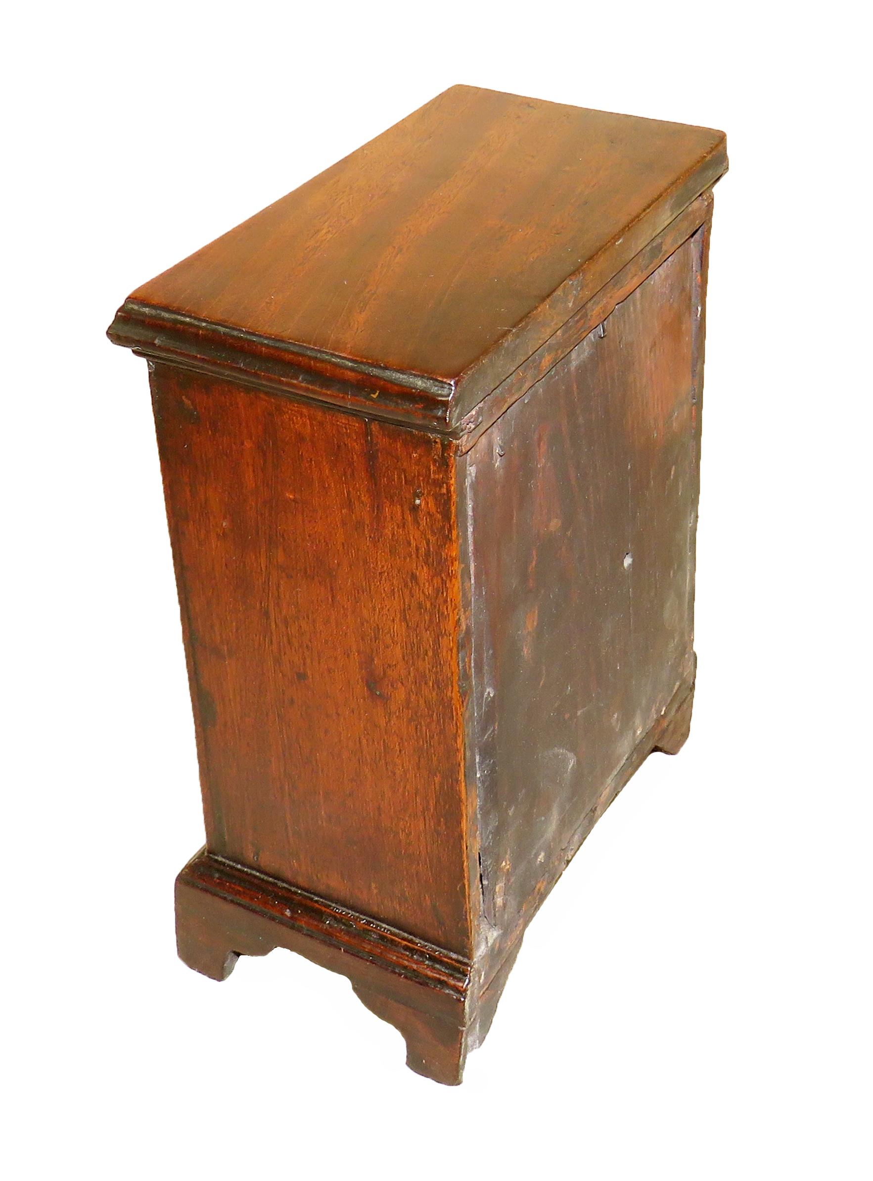 A charming mid-18th century mahogany miniature chest
retaining exceptional untouched color and patina with
two short and three long drawers and original brass
handles raised on original ashaped bracket feet

(Much discussion is had over the