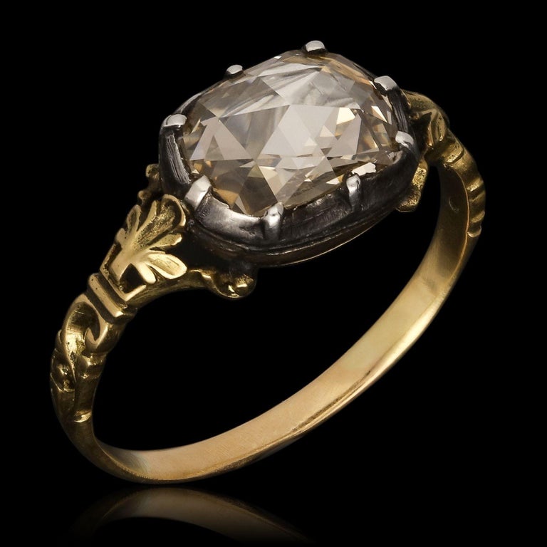 A beautiful Georgian rose cut diamond ring c.1820, set to the centre with a rectangular cushion shaped rose cut diamond positioned horizontally in a silver cut down collet setting with a closed gold button back, between trifurcated fluer-de-lys