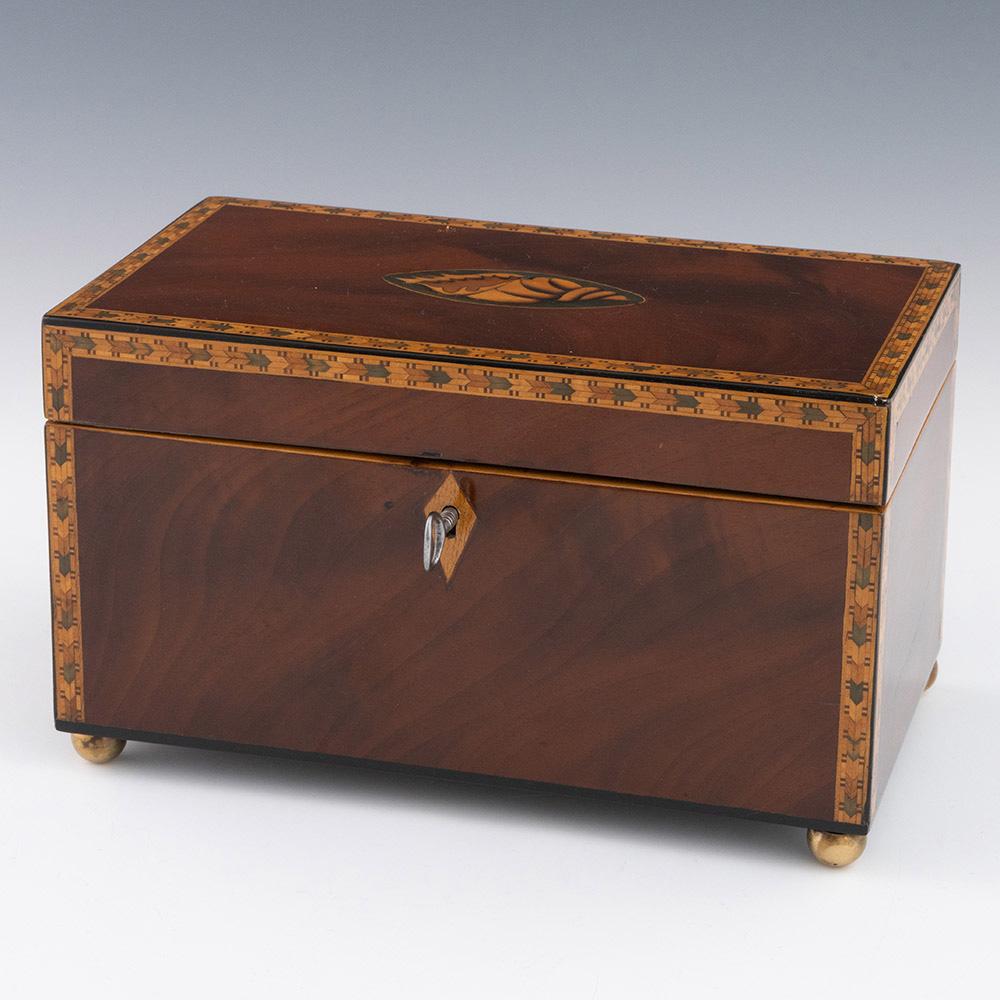 Heading : Georgian antique tea caddy with conch decoration

Date : c1800-1840

Period : George III – Victoria

Origin : Engalnd

Decoration : Magonony with inlaid conch design to centre with polychromatic banding througout. Four ball feet.  Two
