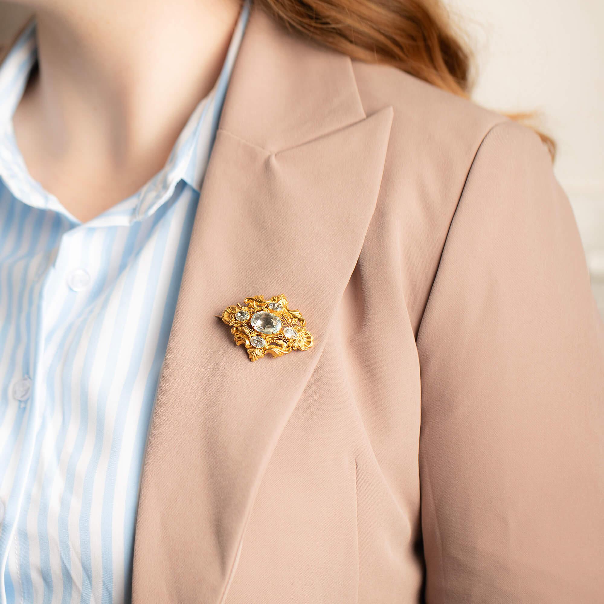 This stunning Georgian brooch features five quatre-foiled aquamarines surrounded by decorative cannetille wire work with hand engraved scrolls with a glass locket to the rear of the brooch. Secured and fitted with pin and hook catch. Presented in