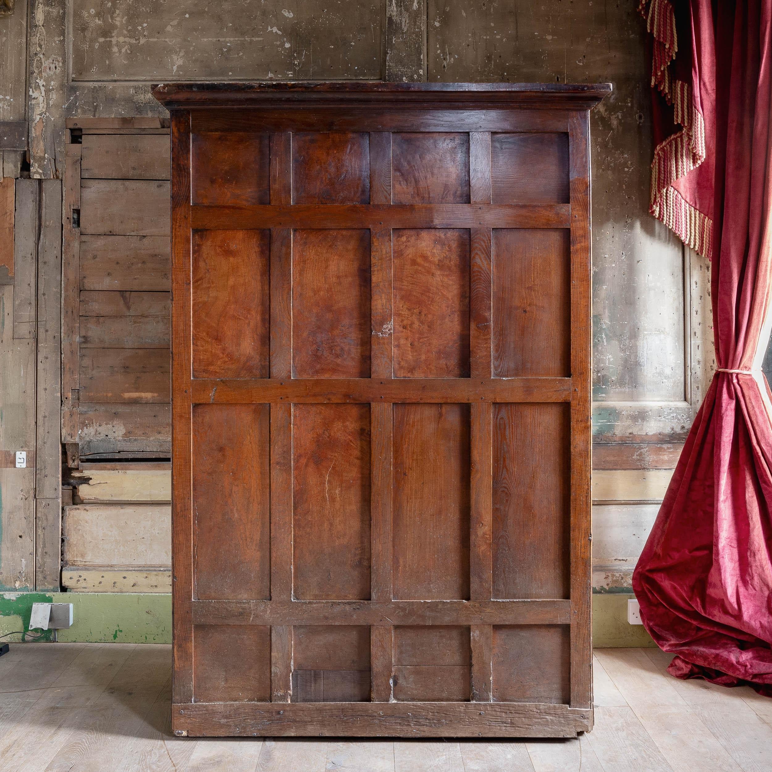 A George III bacon settle, previously in the collection of noted businessman Charles Harold St John Hornby (1867-1946).
Panelled throughout to front and back, the top cupboard accessible via three smaller doors, main cabinet with large wrought iron