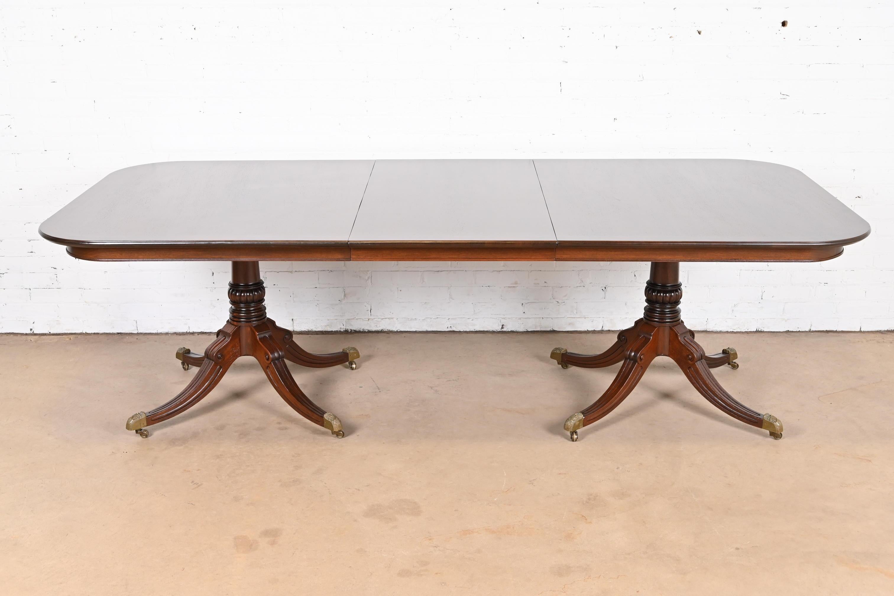 An exceptional Georgian or Regency style double pedestal extension dining table

By Old Colony Furniture Co.

USA, Mid-20th Century

Gorgeous banded mahogany top, with carved mahogany pedestals, and brass capped feet on brass casters.

Measures:
