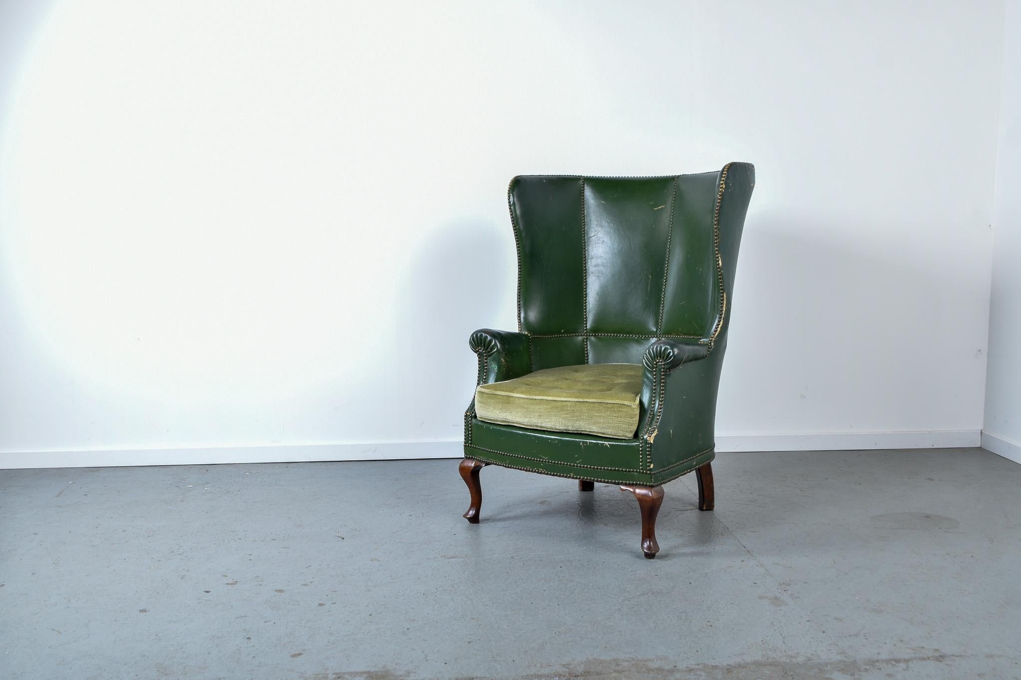 Generously sized barrel back wing armchair with claw feet. 

The chair has a nice patina which adds to the asthetic of the chair.

The chair is upholstered in green leather with brass topped decorative nails and a green mohair seat.

It has signs of