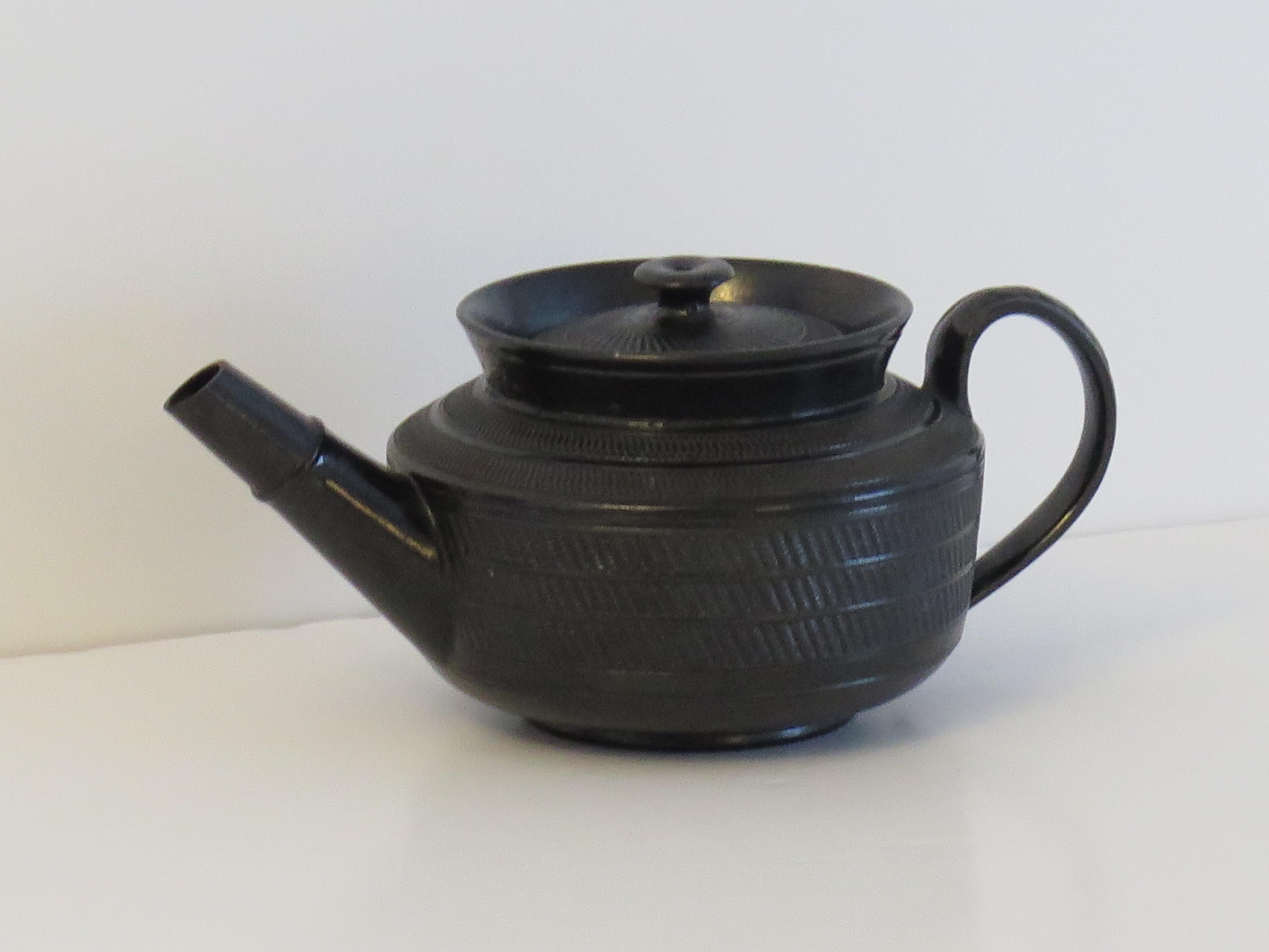 This is a good black basalt Teapot and cover lid, which we attribute to a Staffordshire Potteries, English maker, circa 1825. 

The teapot is well potted with a cylindrical body having an everted top rim, straight tapering spout with raised ring