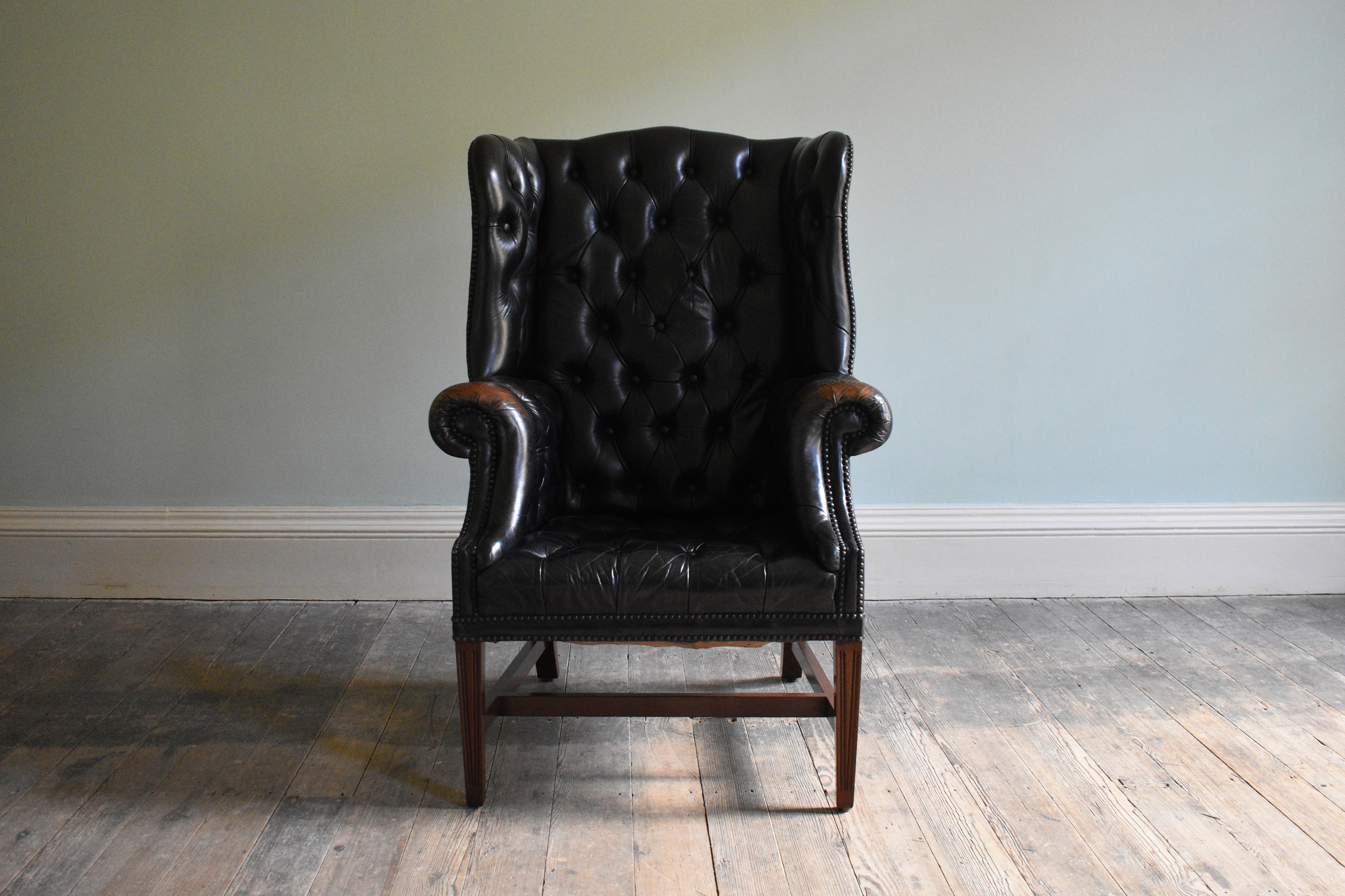 Georgian Black Leather-Upholstered Wingback Armchair

Leather, metal and wood. A fully restored Georgian black leather upholstered wingback armchair. The button upholstered back and slightly bowed seat is outlined with a close nail trim and raised