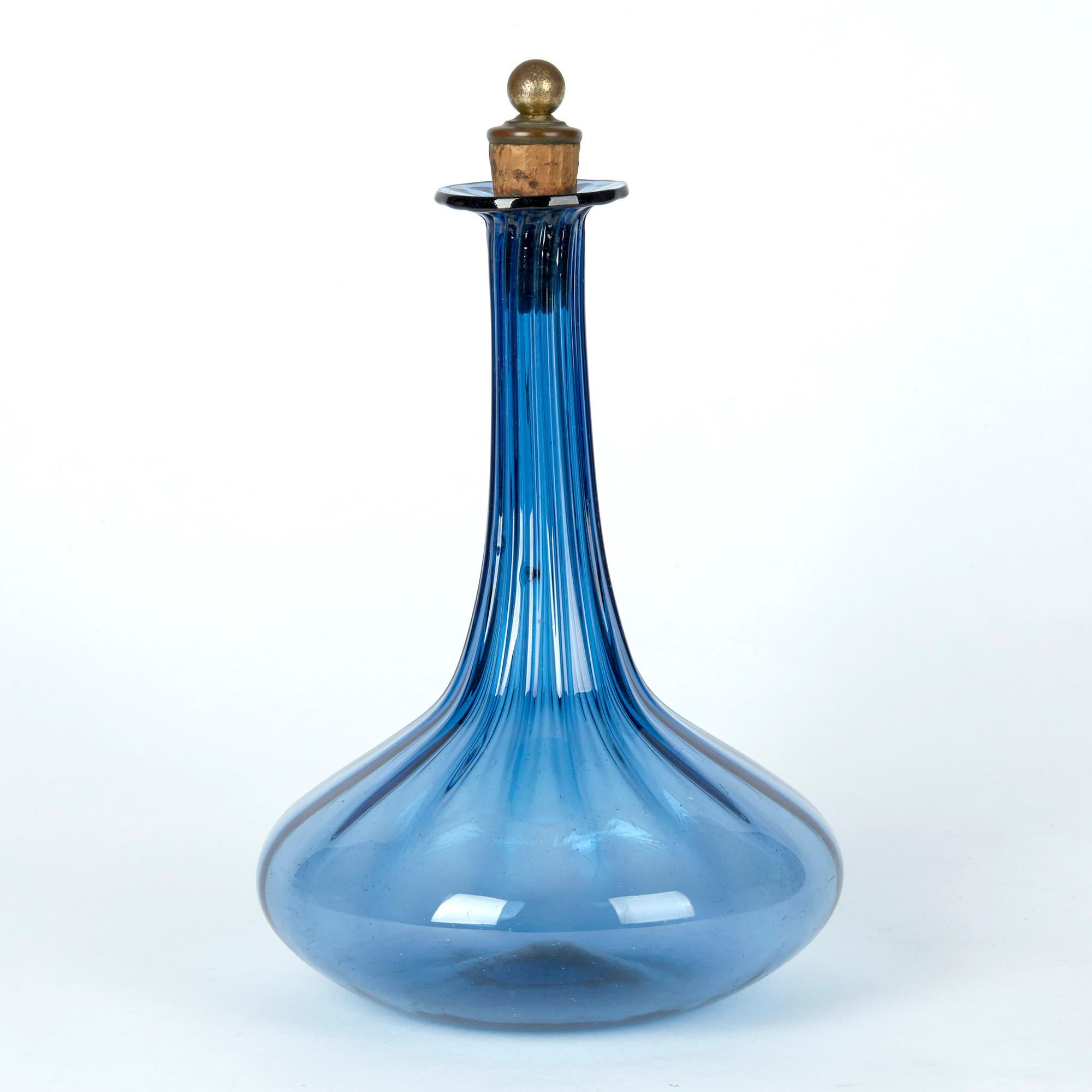An unusual antique Georgian blue glass decanter with ribbed body and cork stopper dating from circa 1820. The decanter has a squat rounded body, tall slender neck and fold back flat drip rim. The hand blown decanter has a flat base with polished