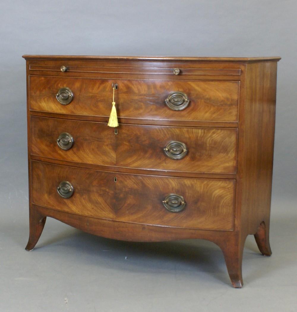 A fine George III bow-fronted chest, of particularly good quality, colour and originality. The chest stands on splay feet with a shaped apron above which are three long, oak lined drawers with butterfly matched Flame mahogany fronts, original
