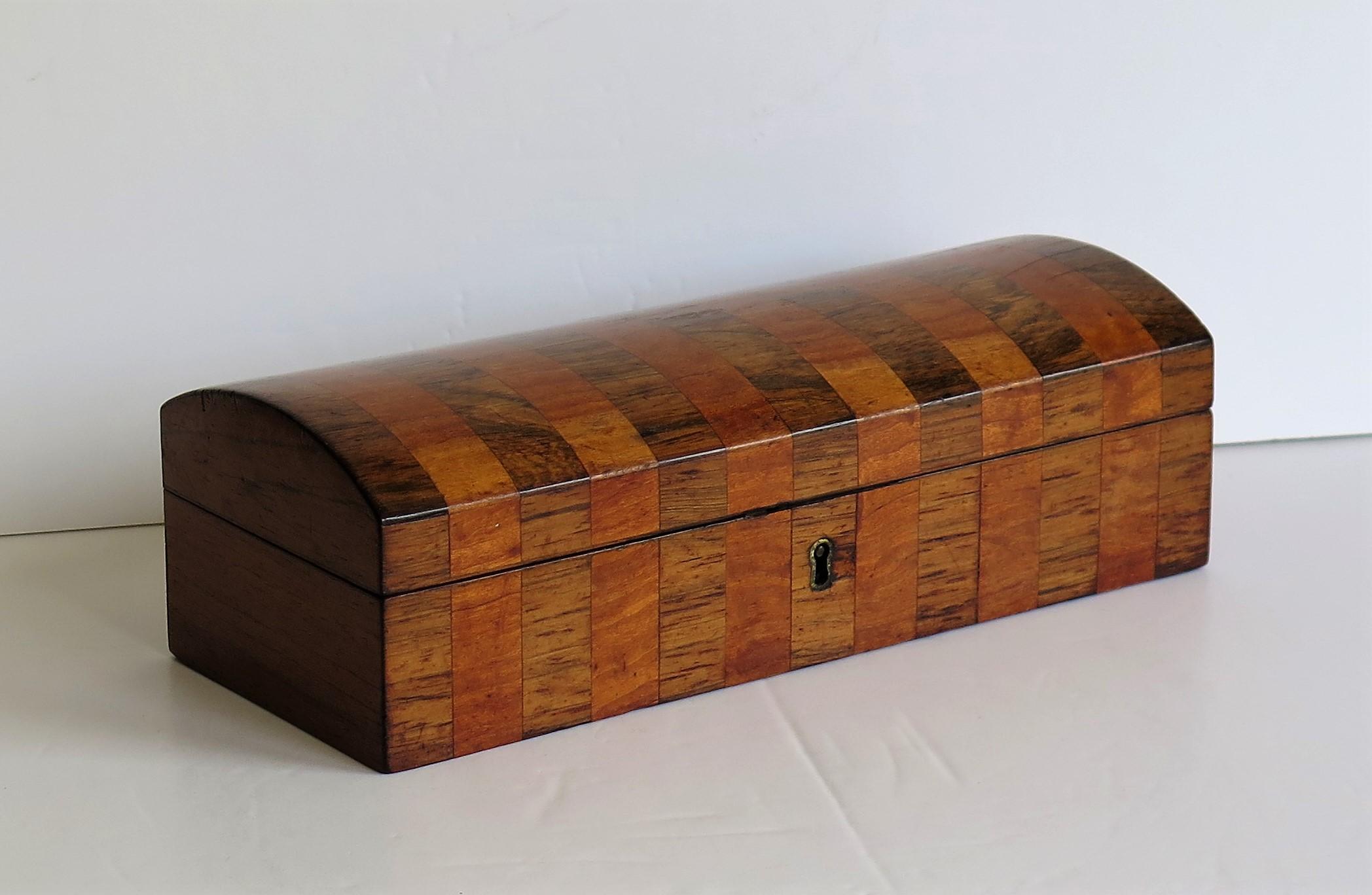 This is a beautiful, fine quality English Georgian period lidded box, inlaid with contrasting crossbanded hardwoods with a hinged domed lid, dating to circa 1810.

The box has a rectangular shape and is handmade of different contrasting hardwoods,