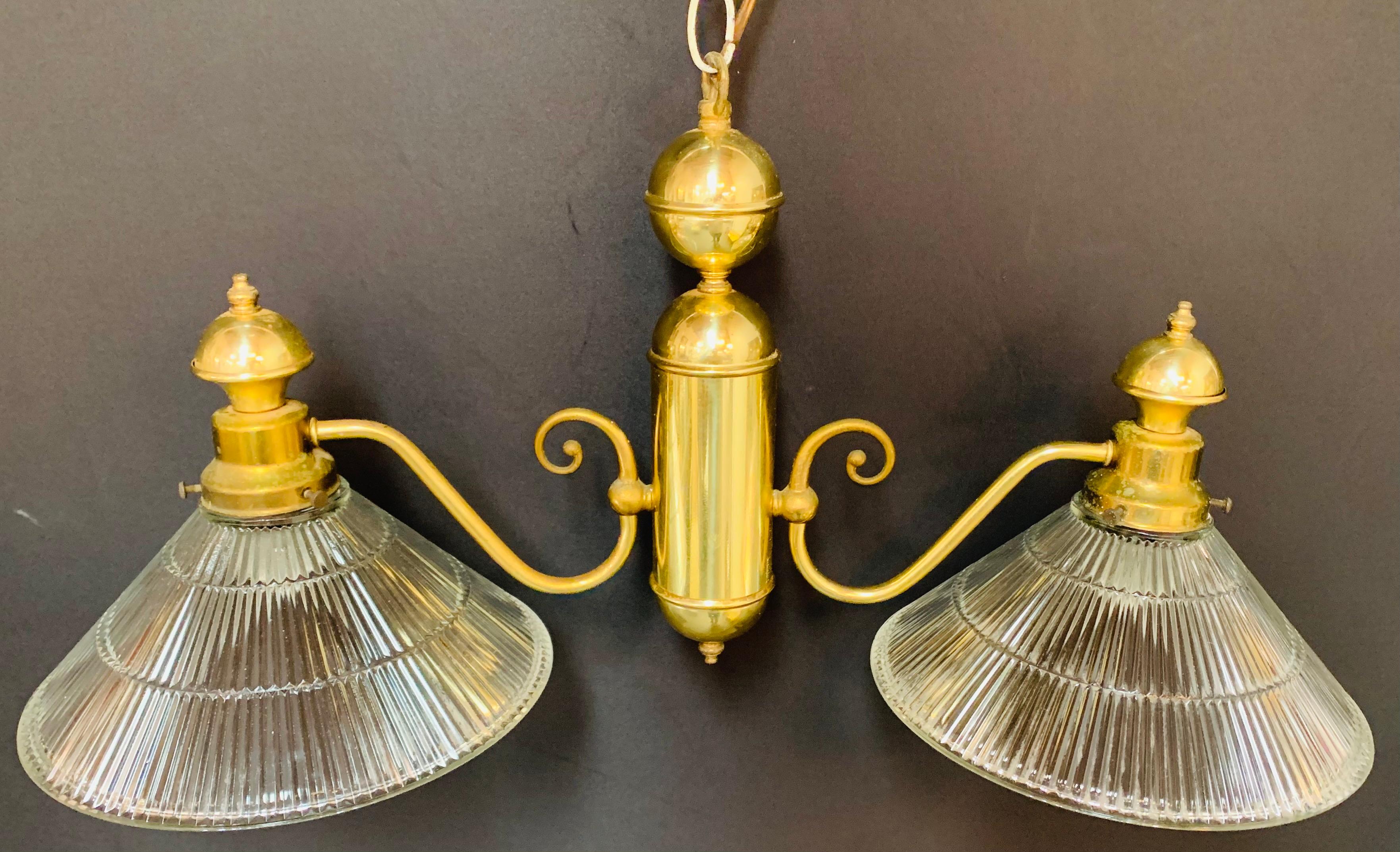 A classy and stylish Georgian style pendant or chandelier featuring two large flared glass shades facing downward. Each arm finely ends in a scroll and attached to a cylindric column. 

Dimensions: 26