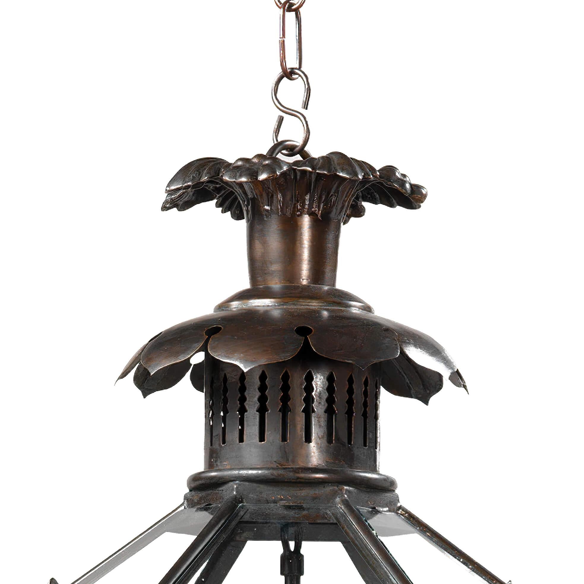 A traditional three-light English George II style hall lantern with a pagoda form crown, anthemion and scrollwork decoration above the hexagonal tapered frame with a reticulated upper section and door finished in an antiqued bronze.

Dimensions: