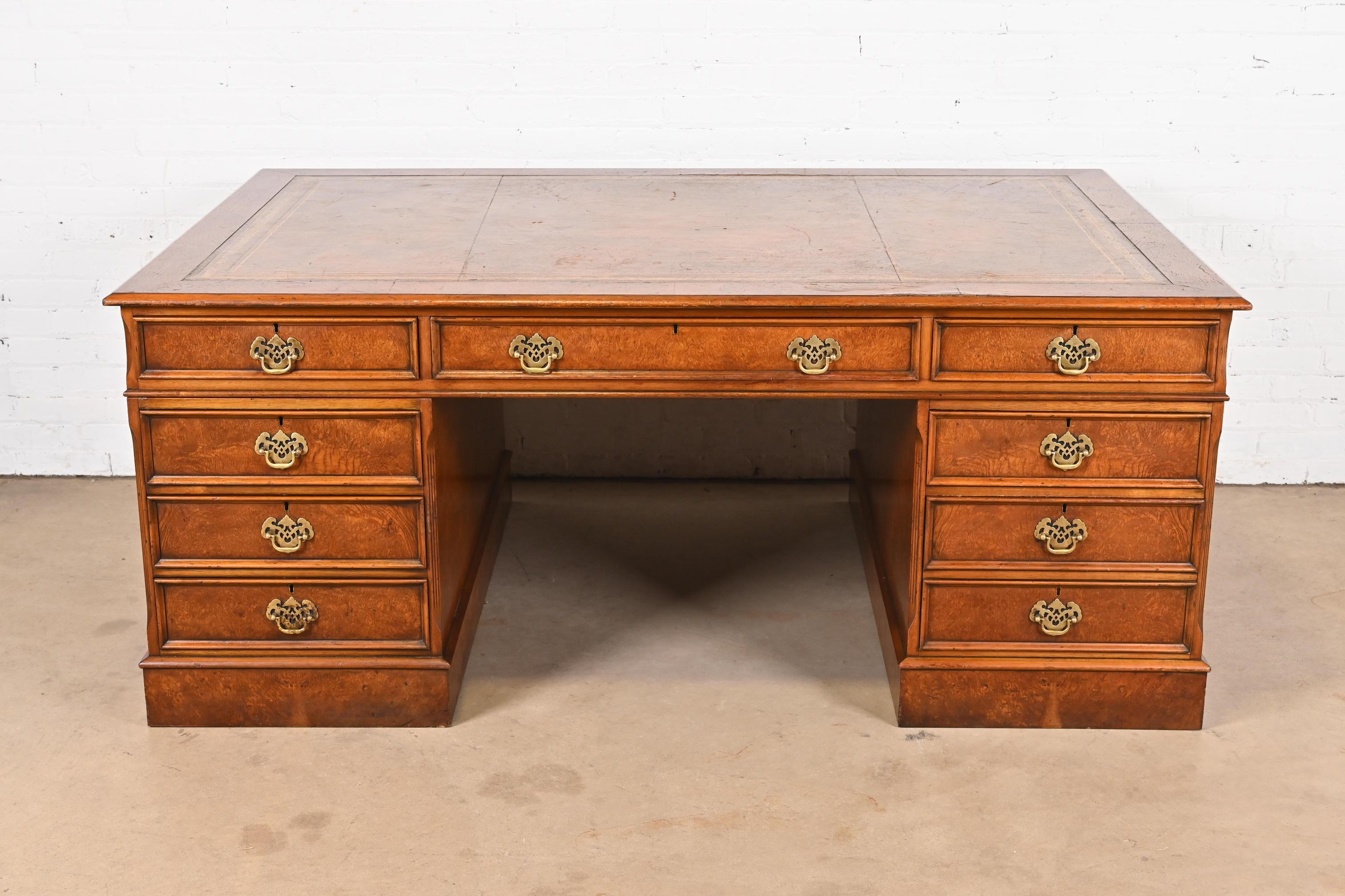 A stately Georgian or Chippendale style double-sided executive partners desk with inlaid leather top

In the manner of Baker Furniture

USA, Circa Mid-20th Century

Gorgeous burled walnut, with original brass pulls and inlaid embossed leather