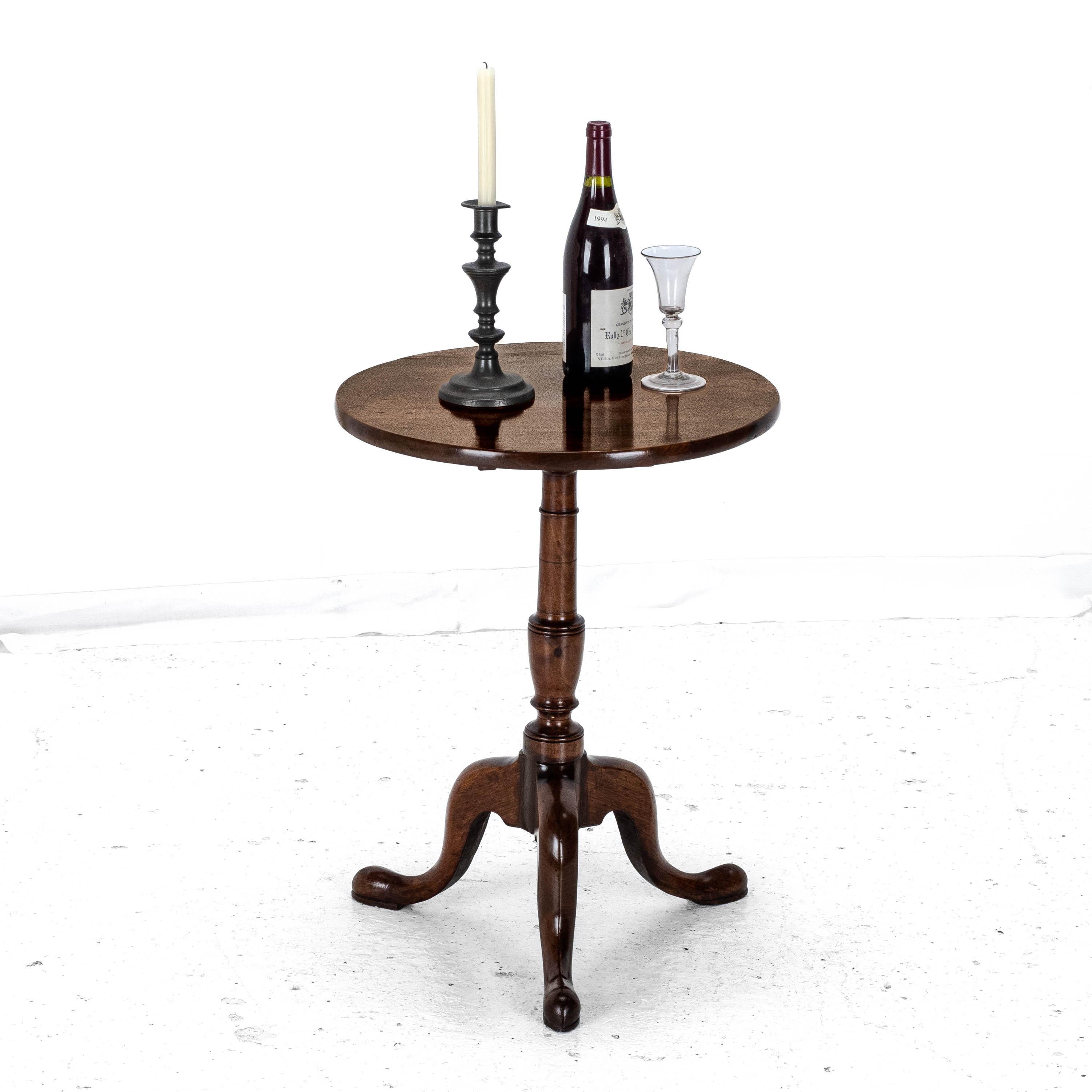 Mesa de vino trípode de caoba del periodo Jorge III, de finales del s. XVIII. Esta atractiva mesa tiene un tablero de caoba maciza de forma circular. Mecanismo basculante abatible. Soportado por un vástago de balaustre torneado, elevado sobre un
