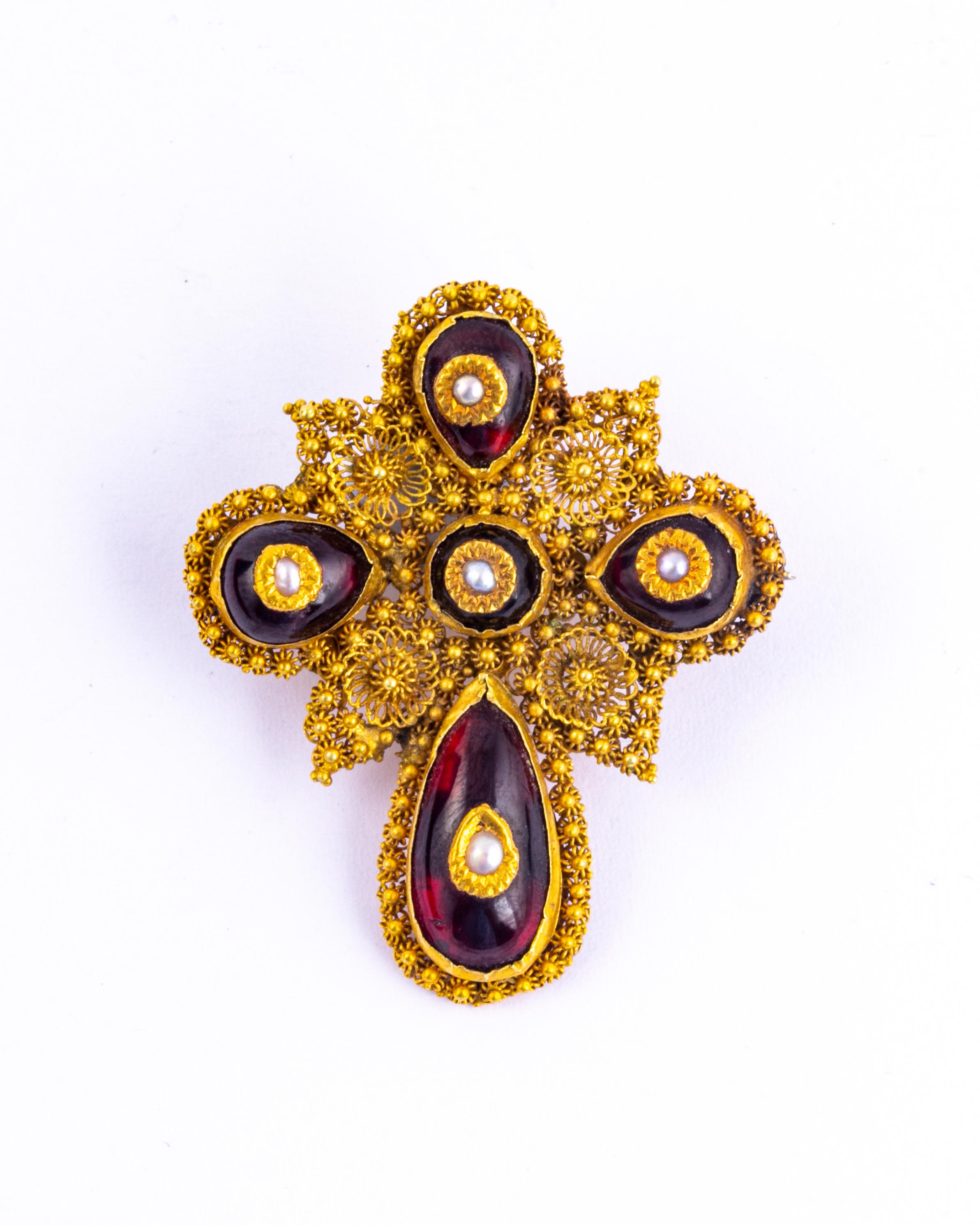 These stunning cabochon garnets are set in yellow gold with intricate cannetille work. Sat on top of these gorgeous red stones are seed pearls in gold petals. The earrings are worn using a shepherds hook and the brooch has a classic pin back. The