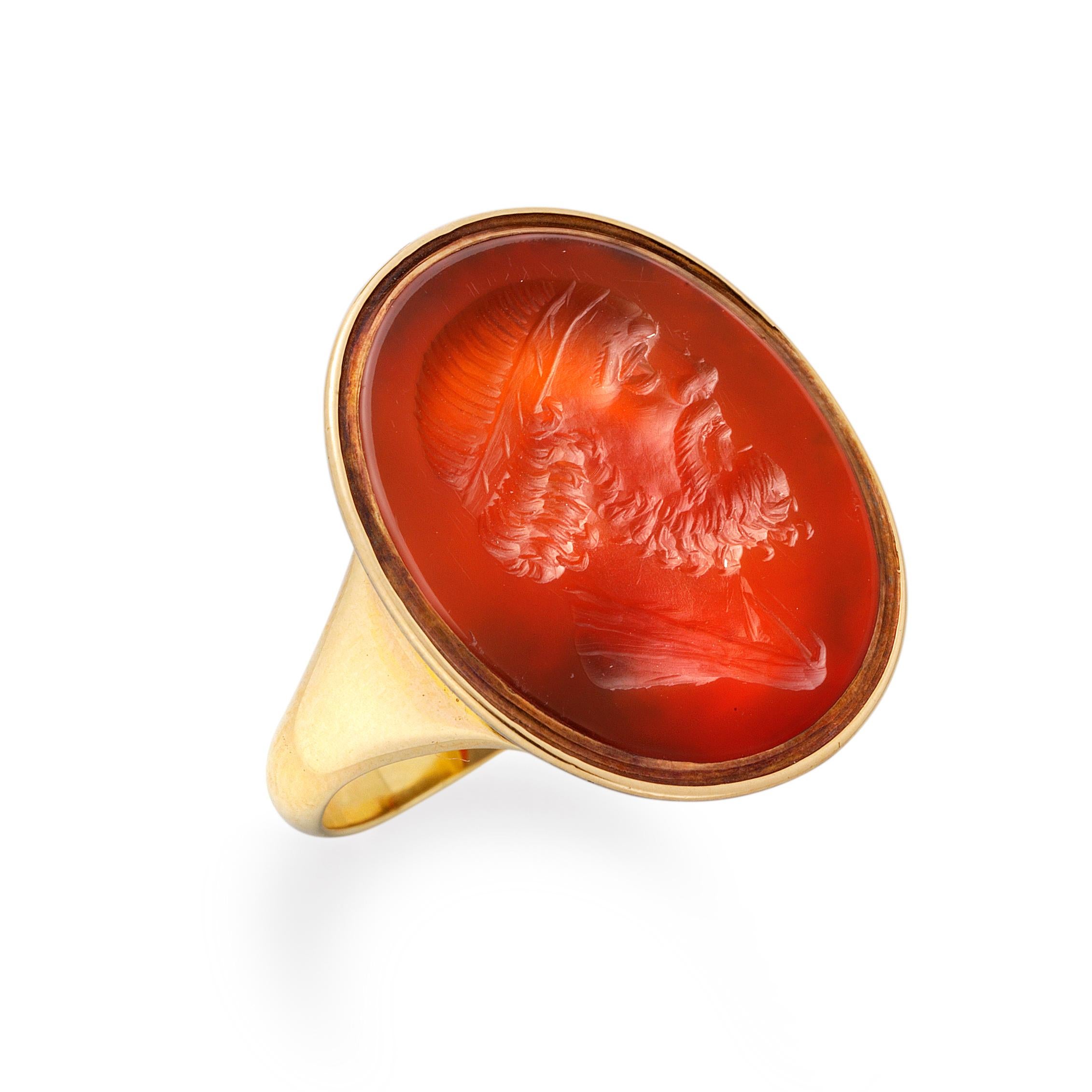 Ein georgischer Karneol-Intaglio-Ring, der ovale Karneol misst 21 x 18 mm, ist mit einem klassischen männlichen Kopf mit Bart und im Profil graviert, in einer Fassung aus Gelbgold mit offenem Rücken und spitzen Goldschultern.

Die Fingergröße der