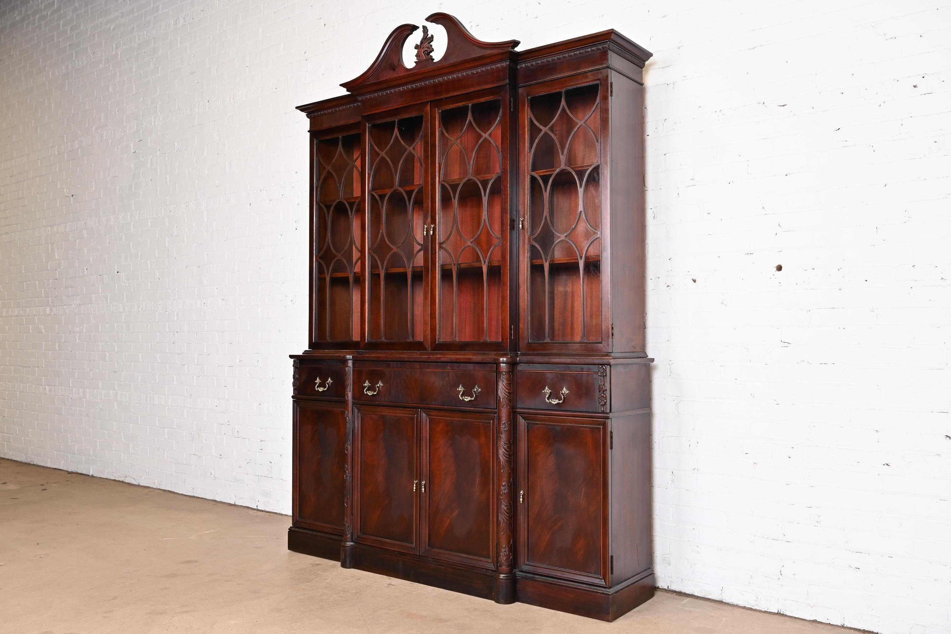 A gorgeous Georgian or Chippendale style breakfront bookcase or dining cabinet with drop front secretary desk

In the manner of Baker Furniture

By Vanleigh

USA, Circa 1930s

Carved flame mahogany, with mullioned glass front doors and original