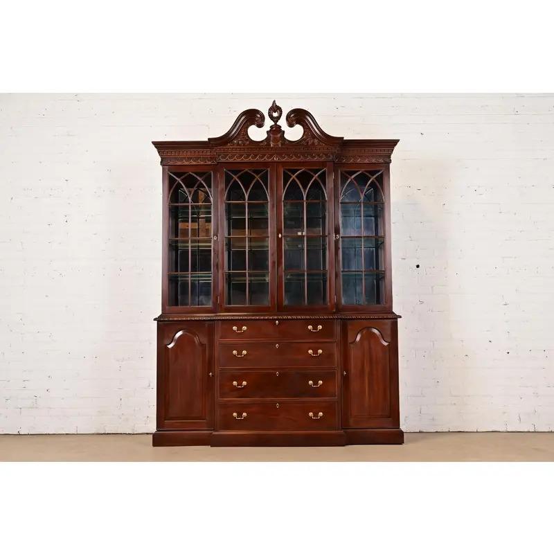 A gorgeous Georgian or Chippendale style lighted breakfront bookcase or dining cabinet

In the manner of Baker Furniture

By Craftique

USA, Circa 1980s

Carved mahogany, with mullioned glass front doors, mirrored back, and original brass hardware.