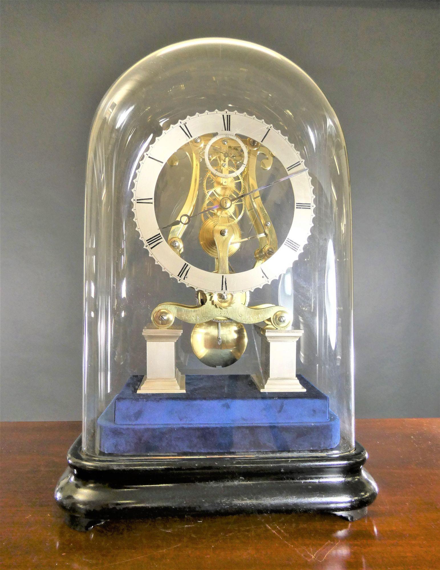 Georgian Skeleton Clock by Jones, The Strand, London
 
Georgian skeleton clock standing on an ebonised stepped base lined with blue velvet and original square glass dome.
 
Lyre shaped plated frame standing on raised rectangular silvered
