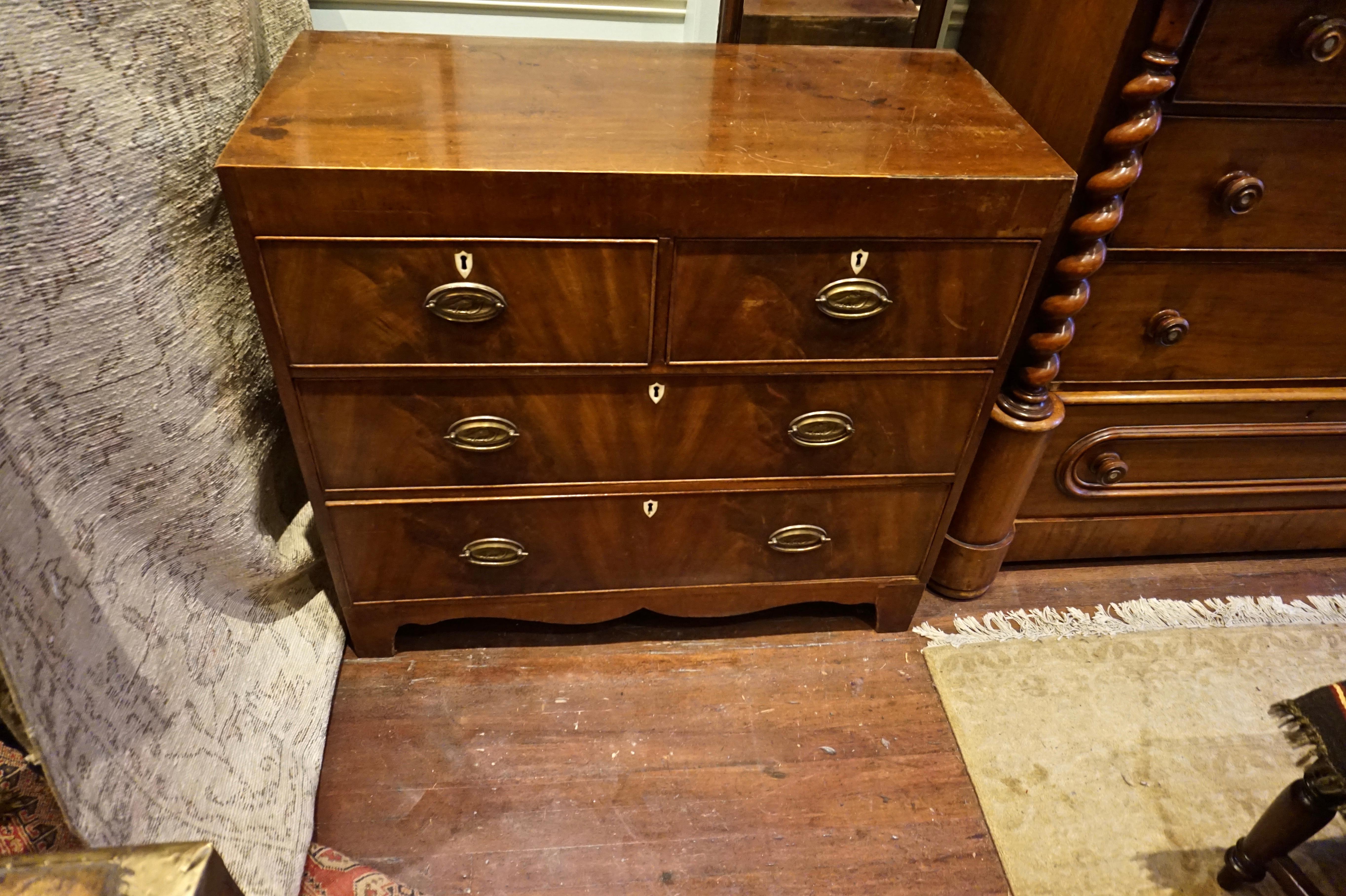 Flame mahogany chest of drawers from the Georgian era with dovetail joints, patinated oval brass handles depicting a bird in flight. Original hardware and ivory key holes standout on the graduated drawers,
circa 1810-1830.
 