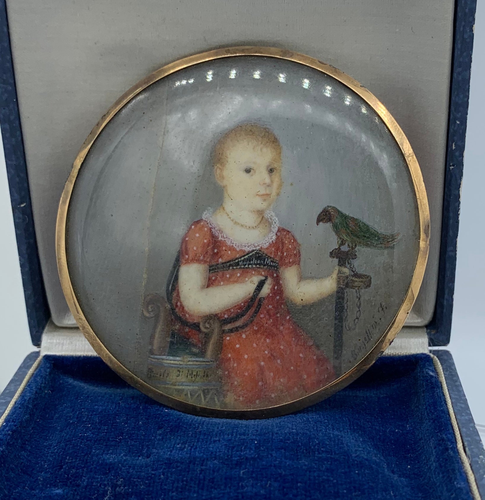 This is a very early and rare Museum Quality Georgian hand painted portrait miniature of a girl child with a bird which appears to be a parrot or raven or crow and is framed in a 14 Karat Gold Frame.  The portrait miniature is of the highest