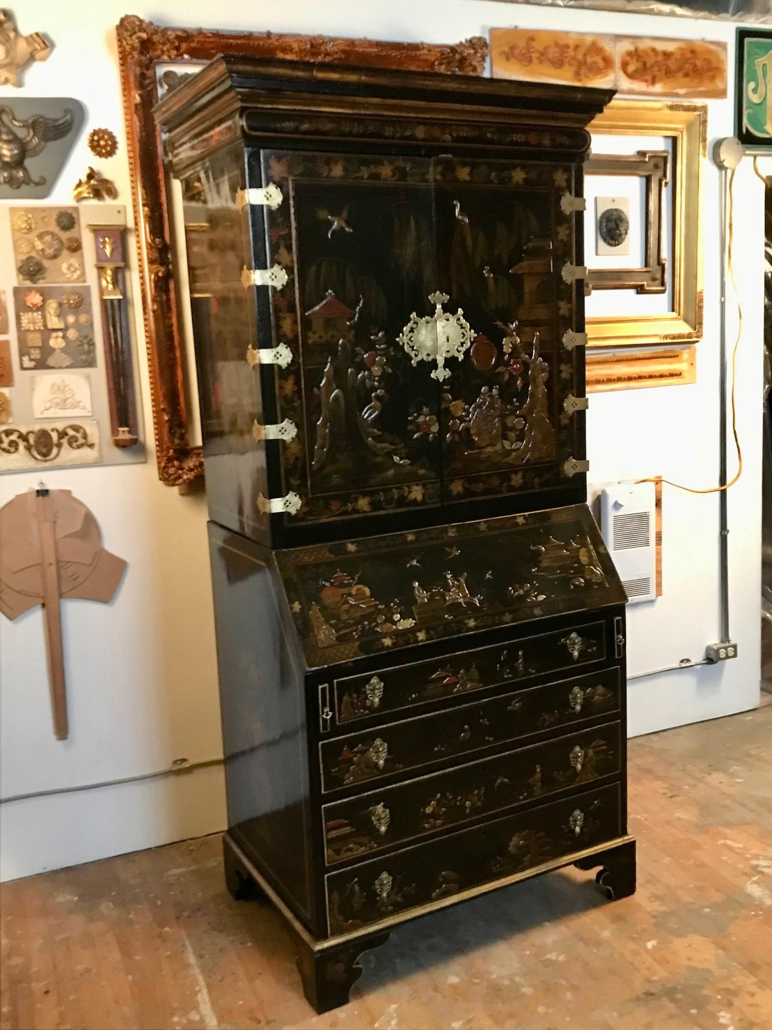 An 18th century English Chinoiserie Bureau Bookcase, profusely lacquered with exotic birds in a flowering landscape, pavilions and “oriental” figures on a black ground. The upper section is enclosed by a pair of doors, the lower has a fall front and