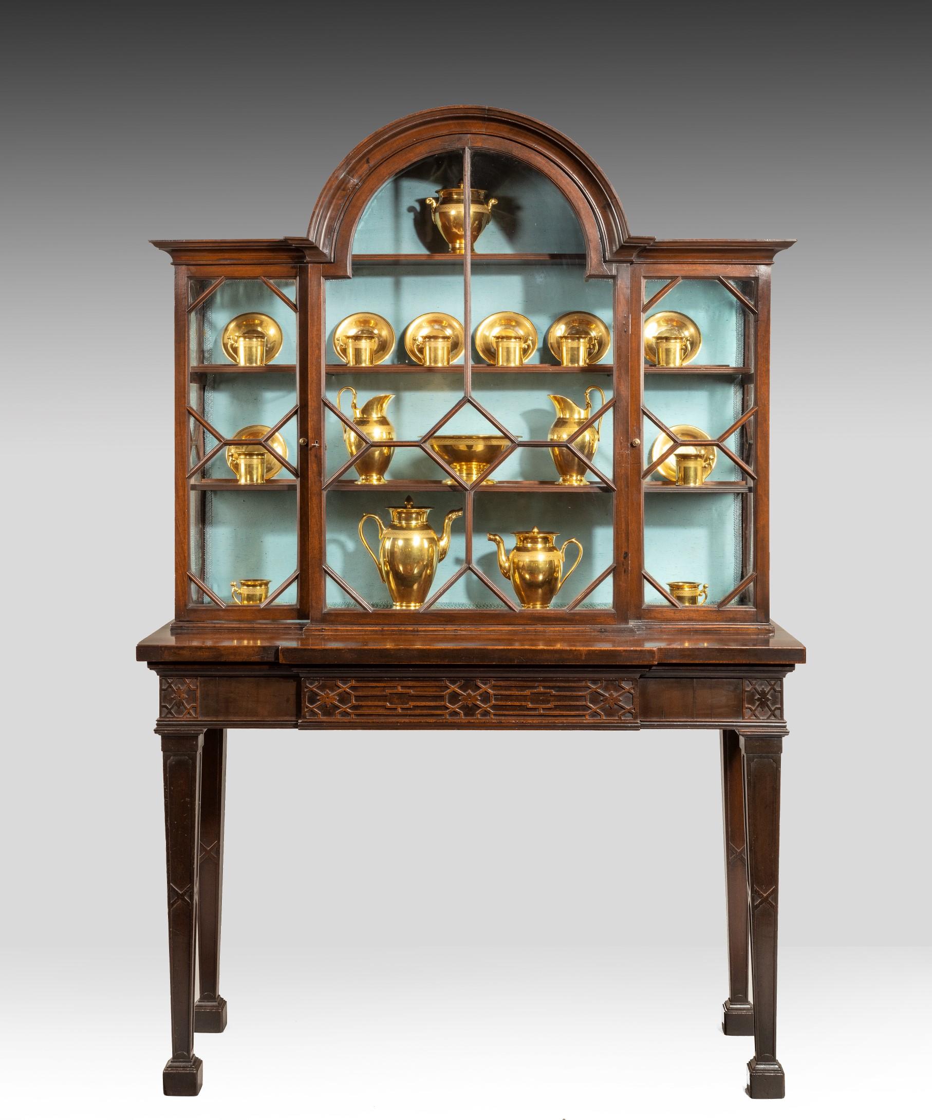 An elegant George III Chippendale period mahogany breakfront china cabinet: the glazed upper section with a central arched door flanked by a pair of doors each with geometric bullnose astragal glazing. The cabinet is raised on its original stand