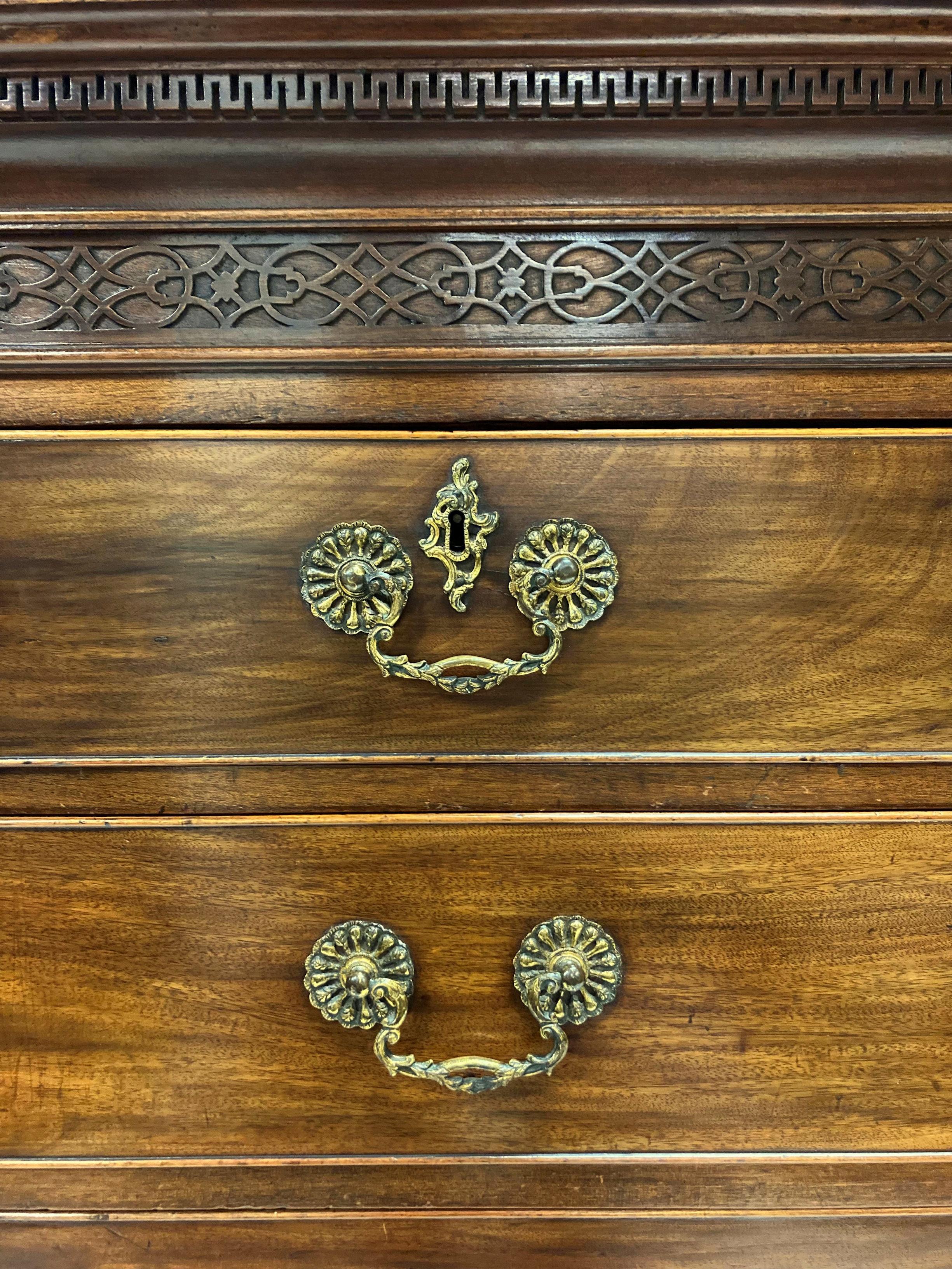 A finely proportioned English George III Chippendale period chest of drawers in mahogany. With a Greek key and fretwork upper frieze, each drawer with the original ornate handles and escutcheons.