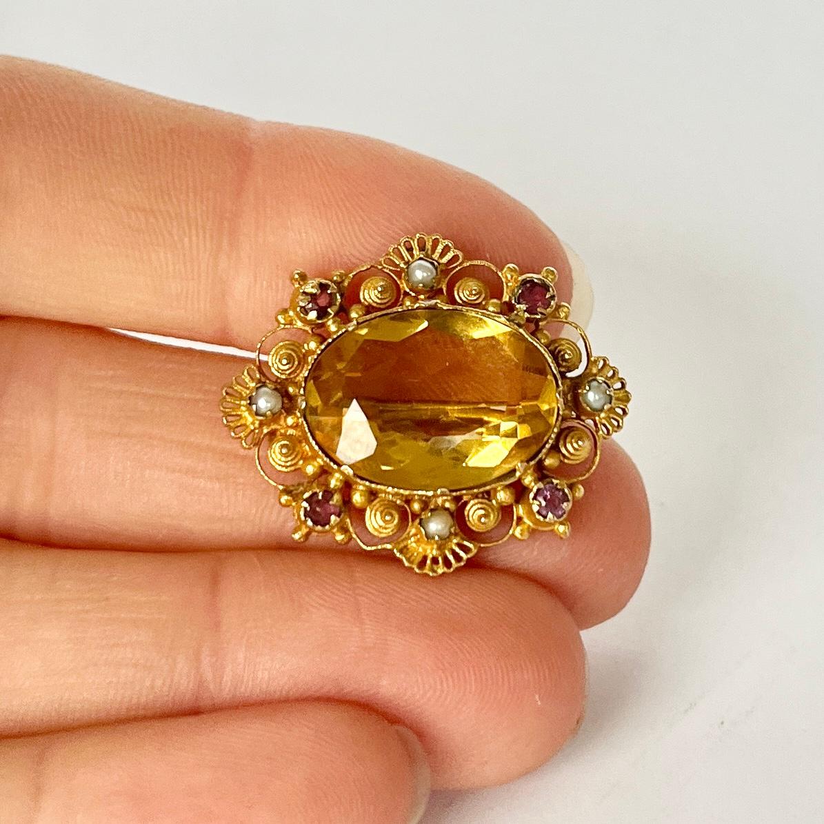 This exquisite brooch holds so much delicate detail. The gold is sculpted into scrolls, swirls and rope twists. The main event is the citrine stone and surrounding this are four rubies and four pearls. 

Citrine Dimensions: 16x12mm
Brooch
