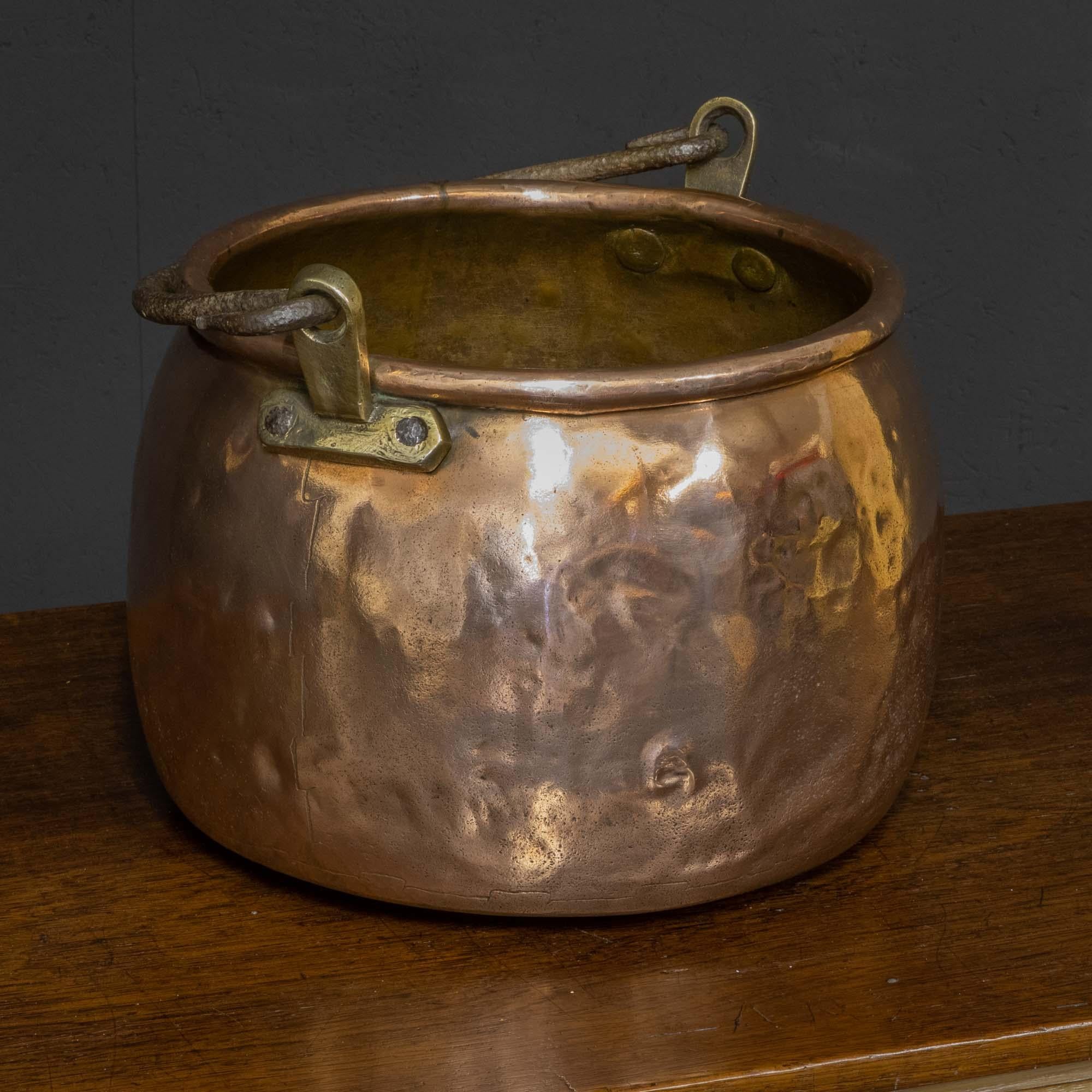 A wonderful early 19th century copper cooking vessel of very heavy duty manufacture. The round body has a large wired edge to the top on the underside of which are a pair of thick brass mounts which give great support for the wrought iron handle.