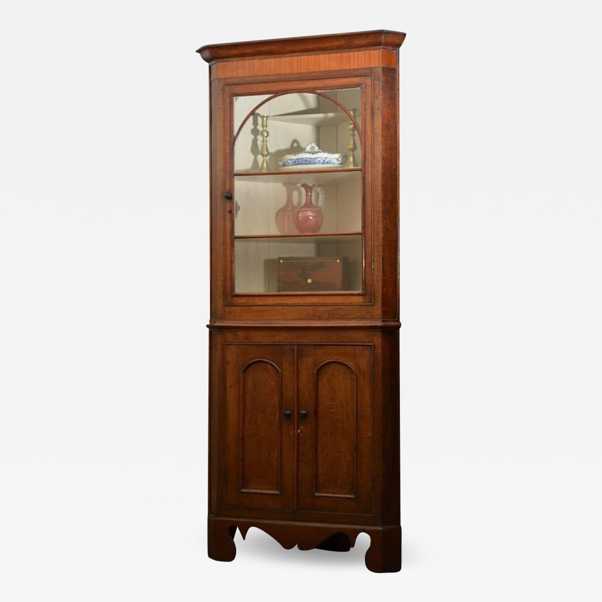 Sn736B Fine example of Georgian, oak and mahogany, freestanding corner cupboard of unusual small proportions, having moulded cornice with mahogany crossbanded frieze below, single glazed door to top section with applied arched tracery bars enclosing
