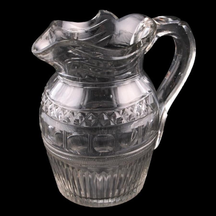 An early 19th century Georgian cut glass water jug.

The jug is slightly grey in colour and the body is profusely cut and facetted.

The shaped handle has a thumb rest at the top and the rim is undulating.

The underside has a ground pontil
