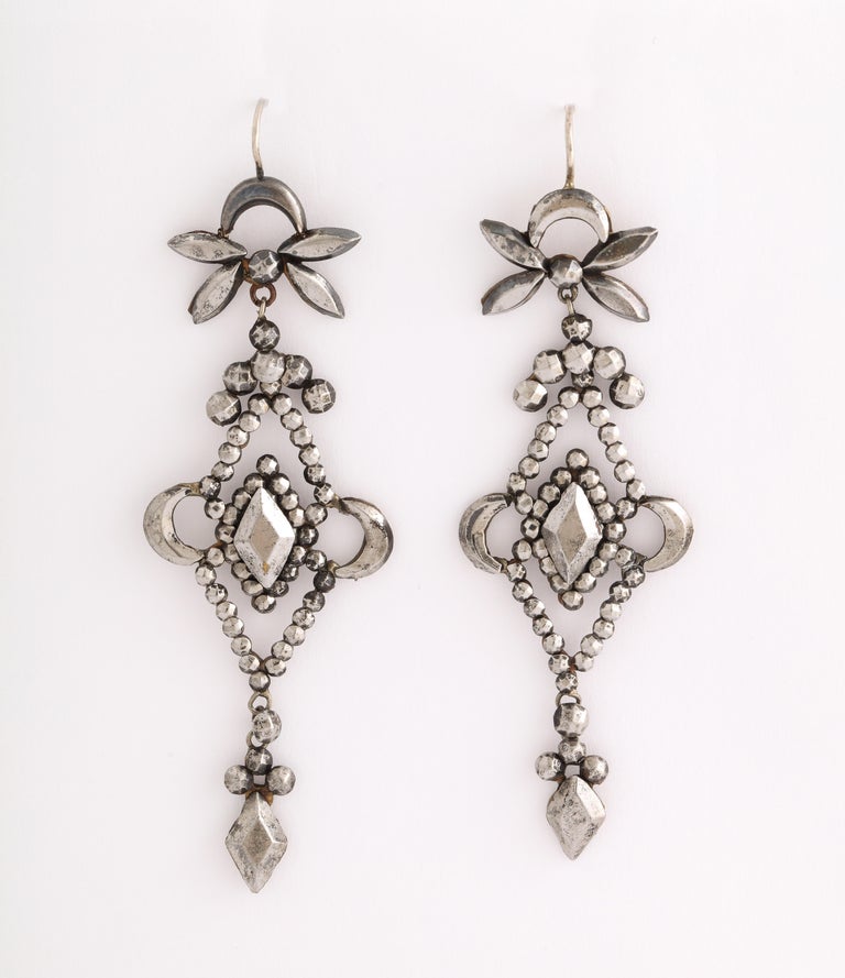 Crescent moons, dragon flies and diamond forms make these earrings a geometric delight. They sparkle even with low light at night. All bits of steel were cut and polished by hand then riveted in place to a form that the jeweler created before he