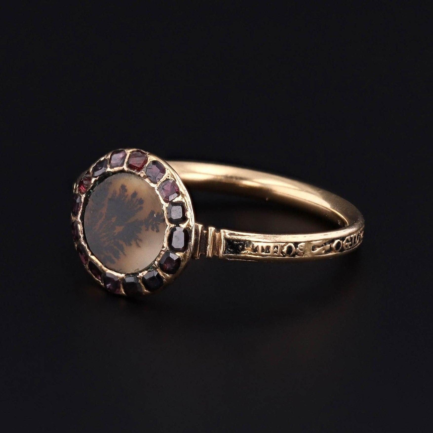 A beautiful mourning ring from the Georgian era!

This special antique treasure commemorates the passing of Thomas Ogilvy in 1766. The face of the 18k gold ring features a dendritic agate encircled by flat cut garnets. The band has black enamel and