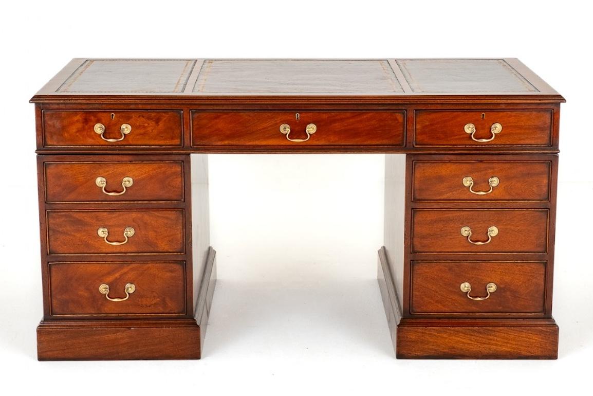 Mahogany Georgian revival desk. This desk stands upon a plinth base and has an arrangement of 9 graduated drawers.
Each of the drawers having brass swan neck handles. The top of the desk having 3 red leather panels with hand applied gilt and blind