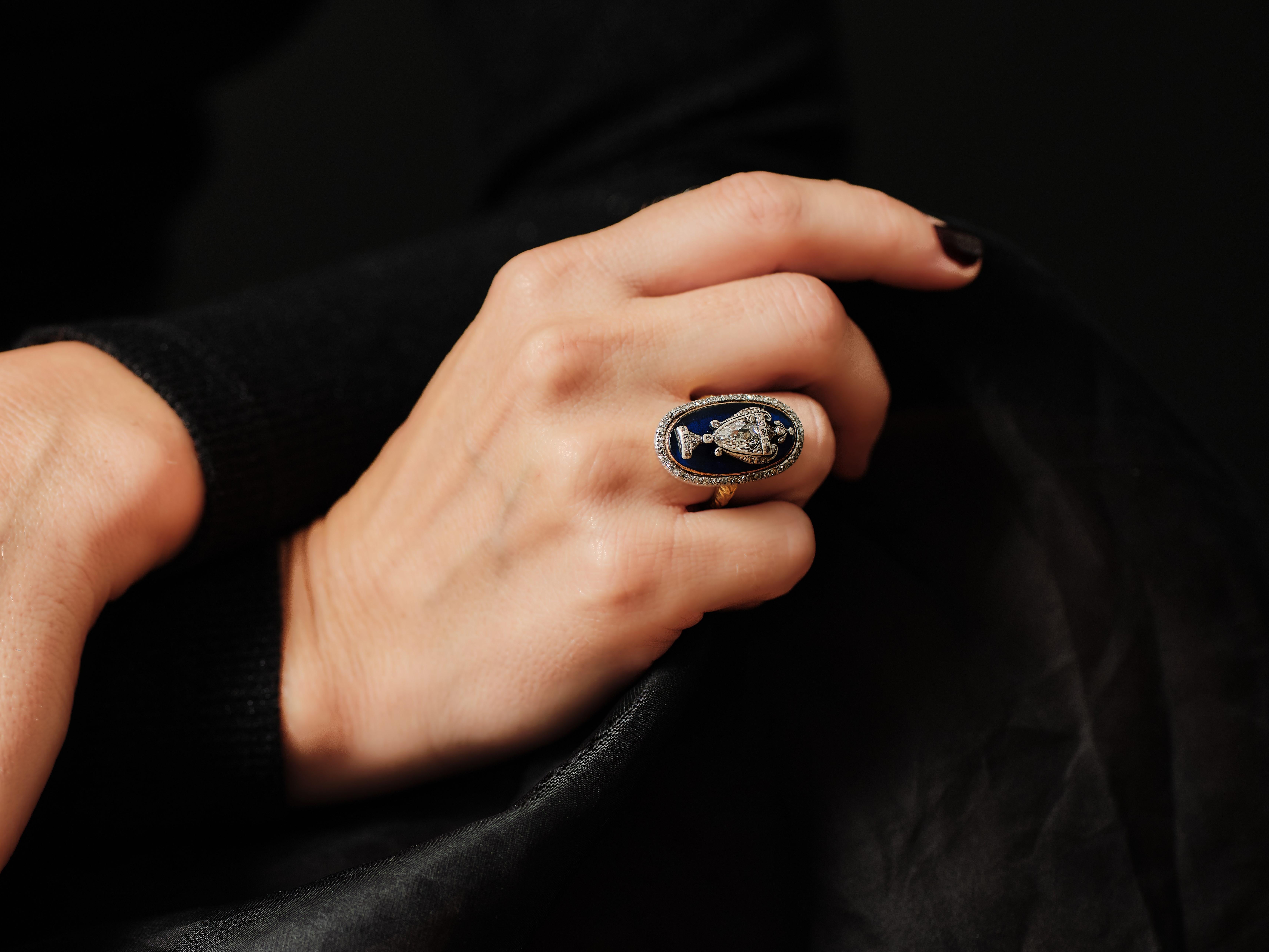 A Georgian diamond and blue glass ring, the oval shaped plaque with a diamond encrusted urn applied on blue glass background and surrounded by a rose-cut diamond-set frame, all set in silver and gold, in gold closed back mount with floral engraving