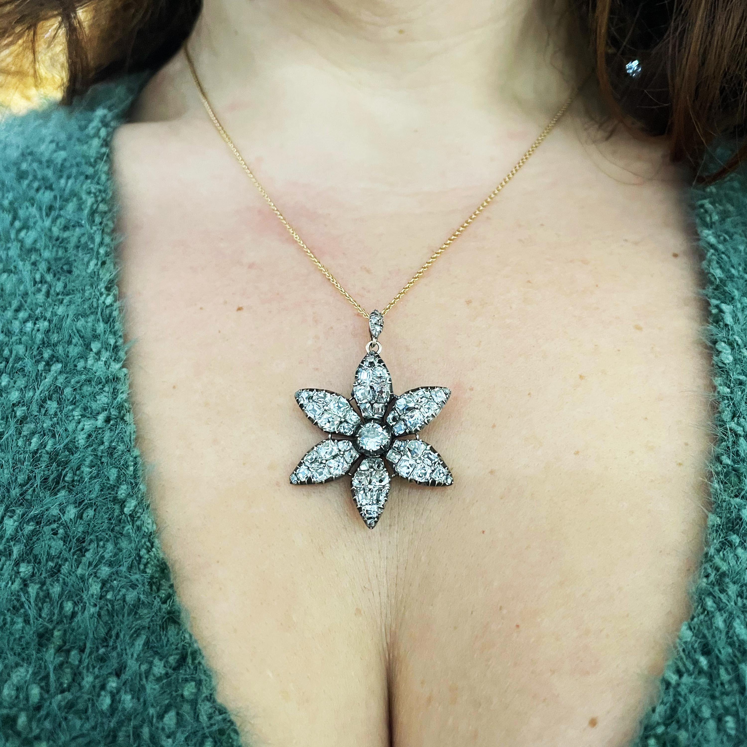 A Georgian old cut diamond flower pendant, with six petals and a diamond set halter, mounted in silver, with scratched inventory marks 7142 C3/-1-, of English origin, circa 1790.

Approximate measurements: Length 32.8mm, width 28.8mm, 42.4mm length