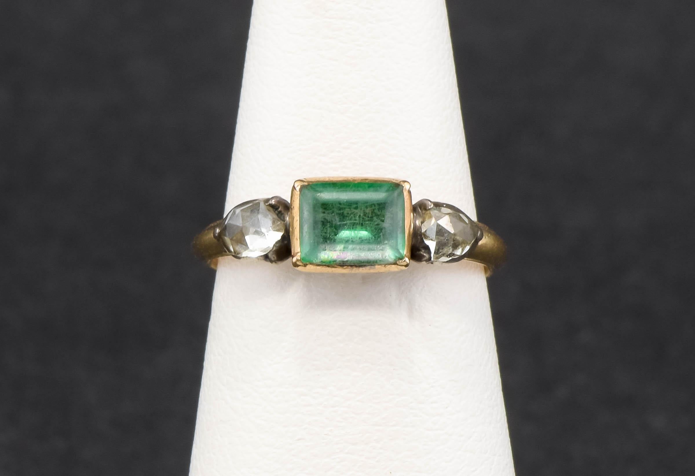 Crafted of gold testing around 18K, with silver collets holding the diamonds, the ring features a rectangular table cut rock crystal backed by green foil to the center, flanked by super chunky rose cut diamonds. In wonderful condition, this ring