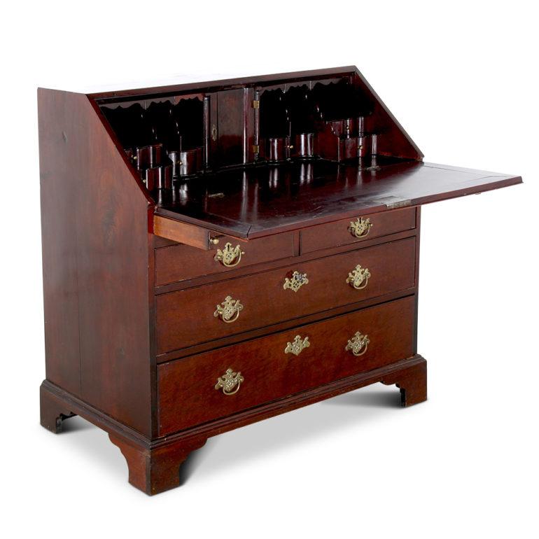 A mid-18th century Georgian drop-front bureau or desk in Cuban mahogany, having three drawers below and an elaborately-fitted interior with ogee-profile drawers and a central inlaid and mirrored ‘room’ which pulls out to reveal hidden drawers