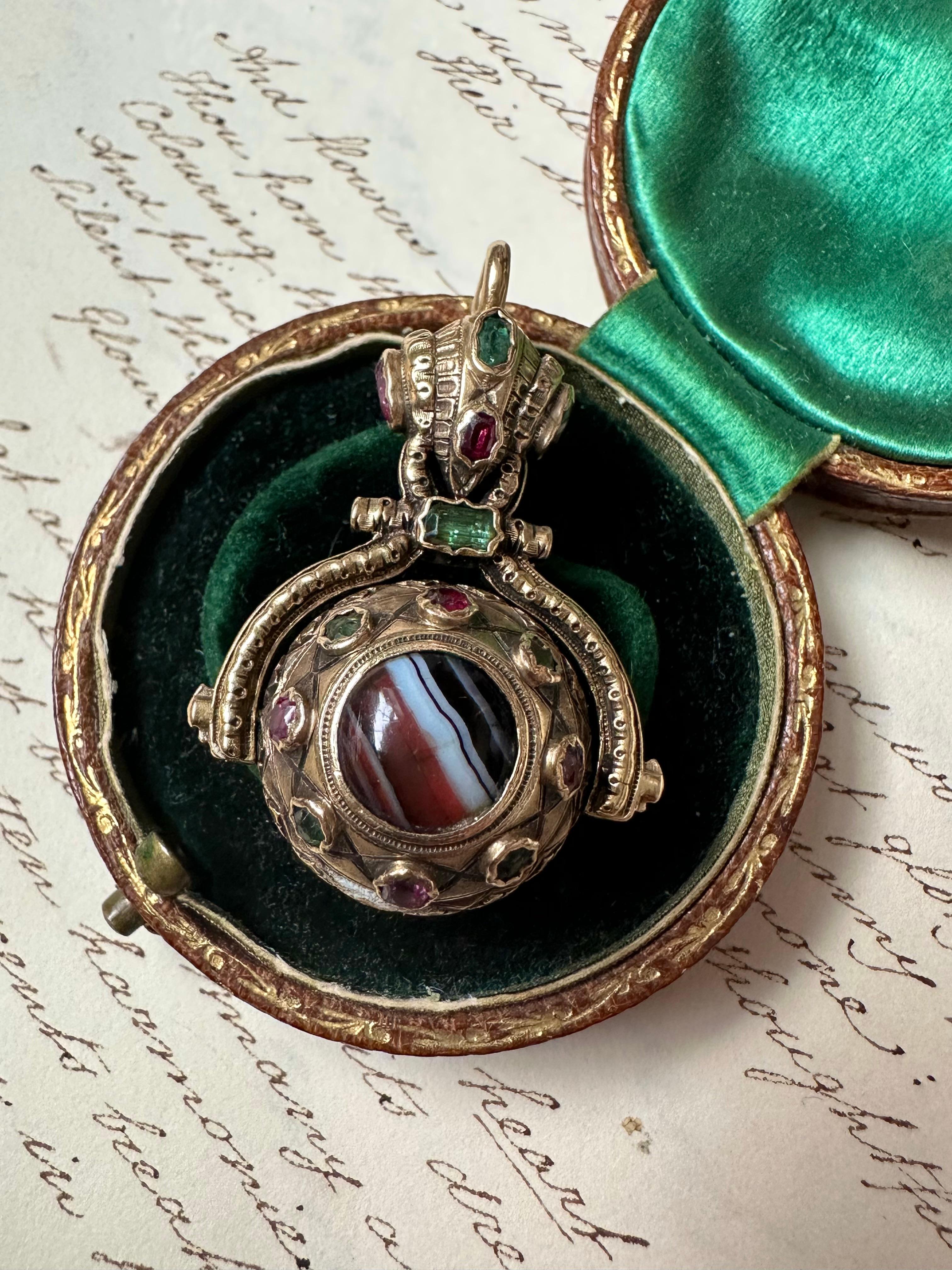 Dating to the early to mid 19th century, this substantial double sided watch fob is a rare and wonderful jewel. One side of the pendant glows with a pastel foil-backed amethyst, the other banded agate adorned all around by gemmy emeralds and vibrant