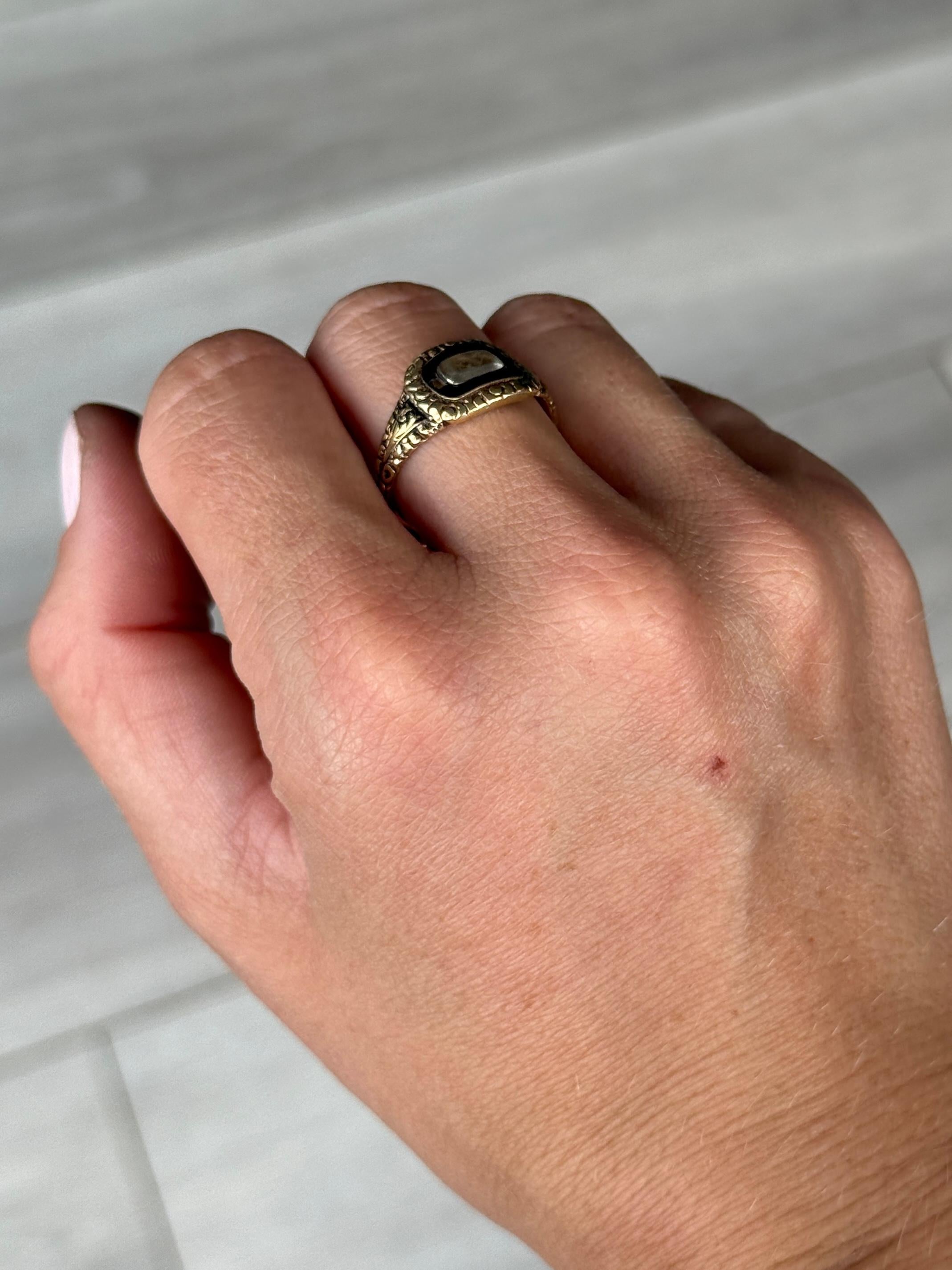 This lovely mourning ring has a decorative band and has enamel around the locket holding plaited blonde hair. Behind the face of the ring there is an inscription. This is hard to read but from what w can make out it reads 'Ob 17, 1829, at 55'

Ring