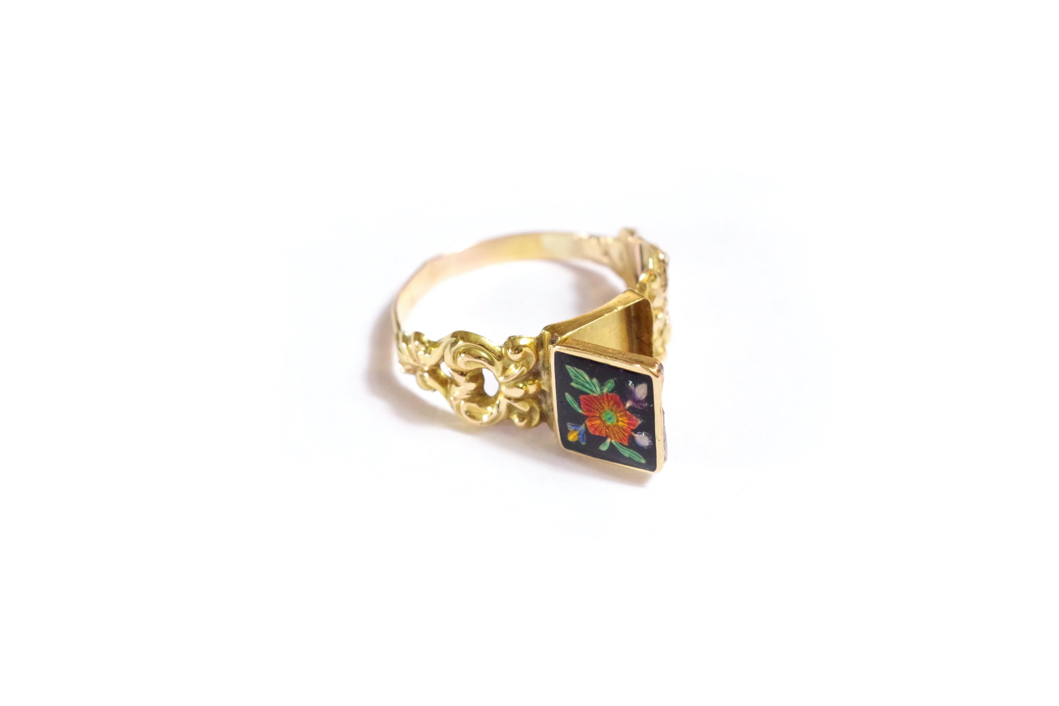 Georgian enamel poison ring in 18 karat yellow gold. Rare ring composed of a square bezel with a secret compartment which opens on the top. The top is decorated with a red enamelled flower on a black background. The ring is richly decorated with