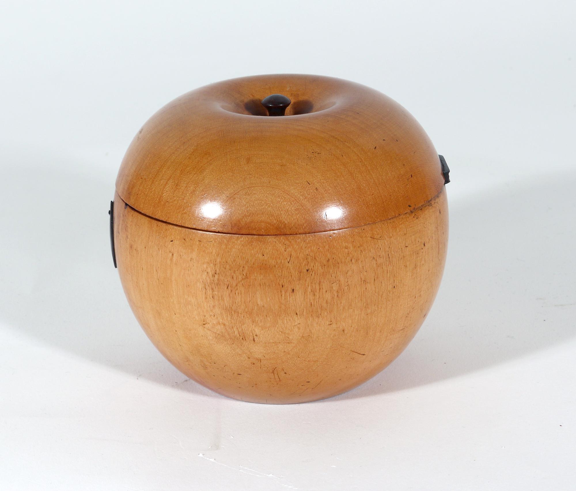 English antique fruitwood tea caddy,
Late 18th century

The antique fruitwood tea caddy is in the form of an apple with a carved stalk in the center of the cover. It was lathe-turned and is in two parts, hinged at the back. It is now with a