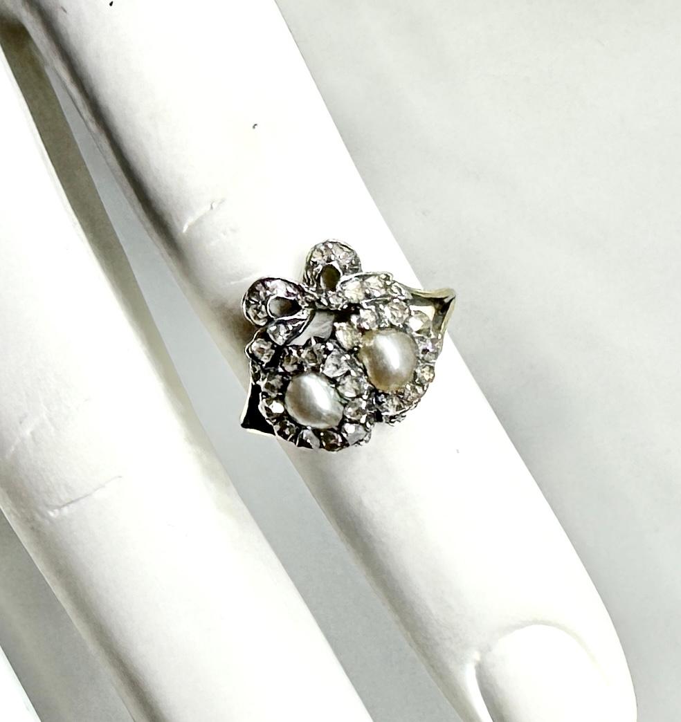 Indulge in a magnificent entwined Heart and Bow Antique Georgian Wedding Engagement Ring with gorgeous pearls and sparkling antique Rose Cut Diamonds set in silver atop 18 Karat Gold as was the custom of the period.  This rare antique jewel dates to