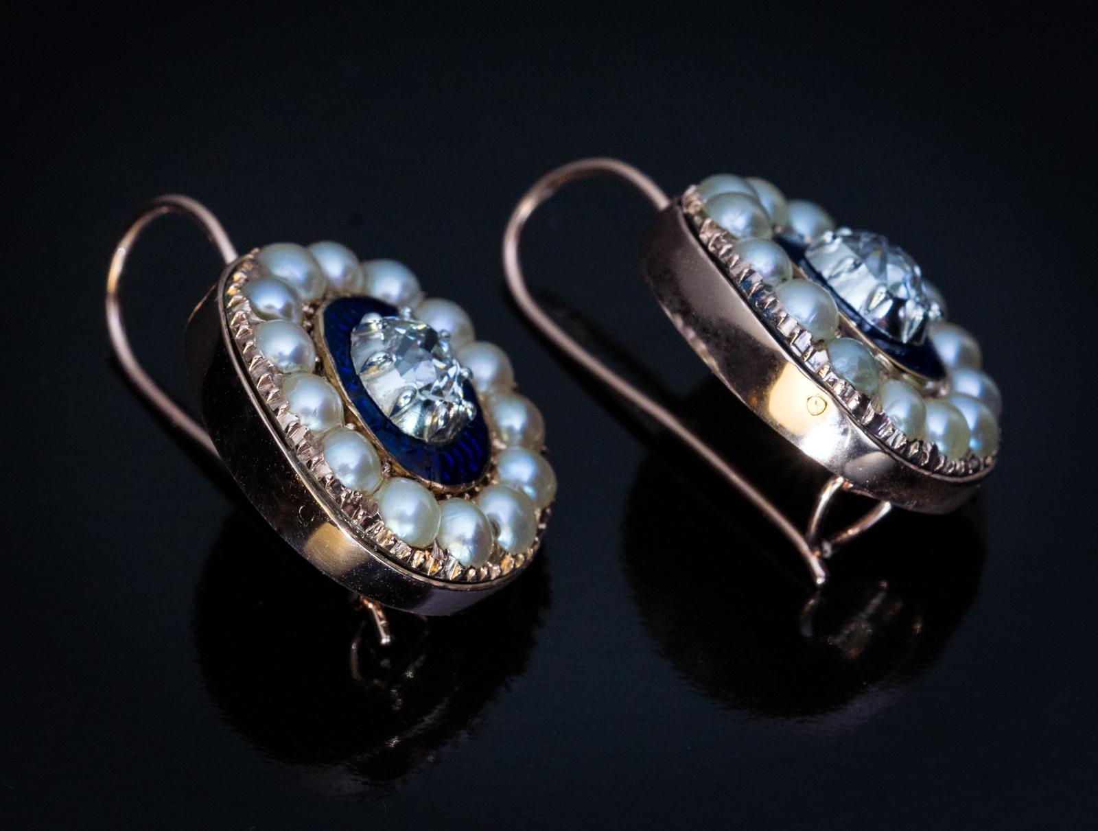 Circa 1810

These very rare Georgian era 14K gold cluster earrings are centered with bright white old cushion cut diamonds set in silver bezels. The diamonds are mounted on royal blue guilloche enamel oval plaques framed by natural