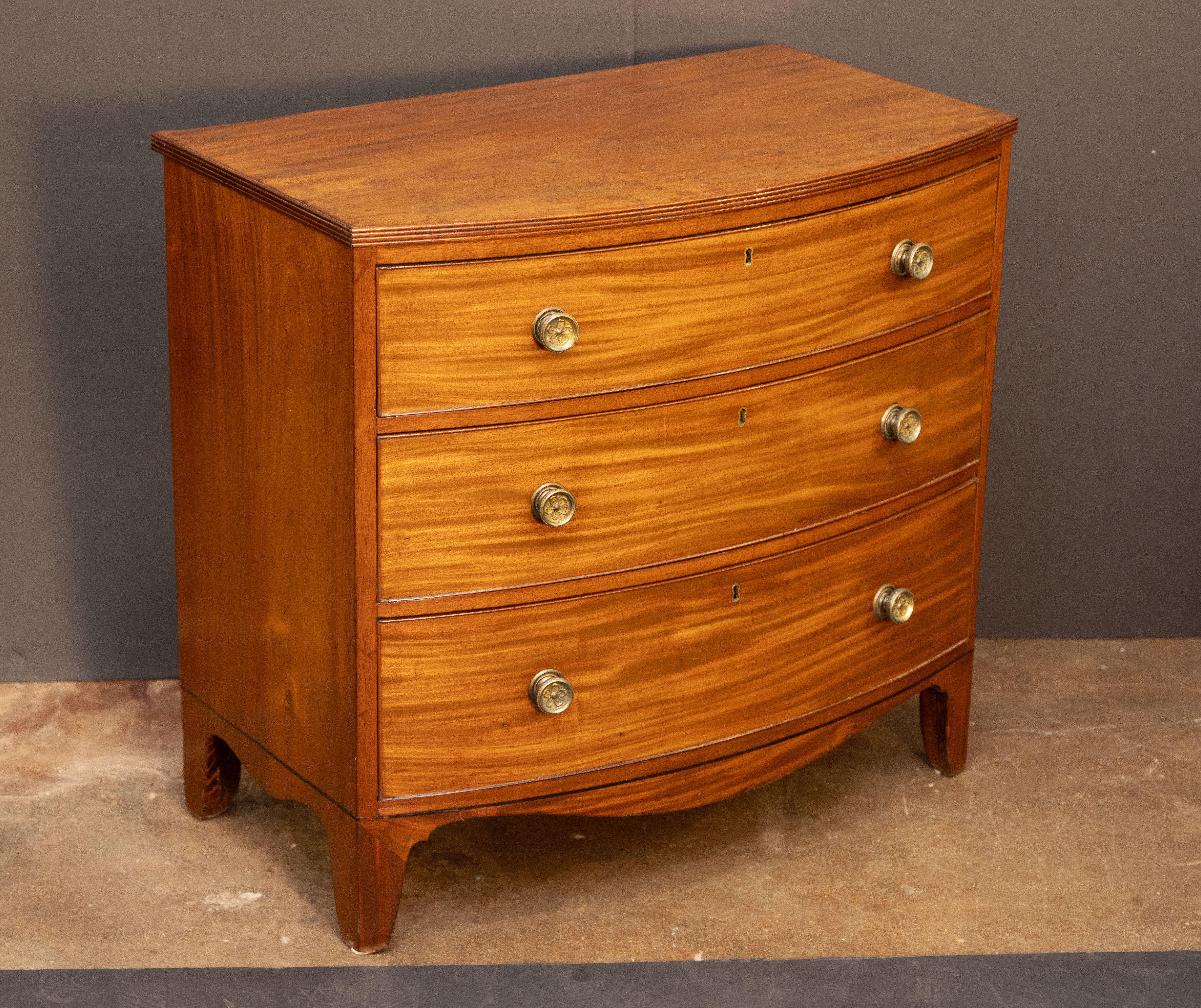 Un raffinato cassettone inglese di epoca georgiana, risalente al 1810 circa, caratterizzato da un piano ad arco con una cornice di perline scanalate intorno al bordo superiore, su un fregio di tre cassetti lunghi con perline, i cassetti con