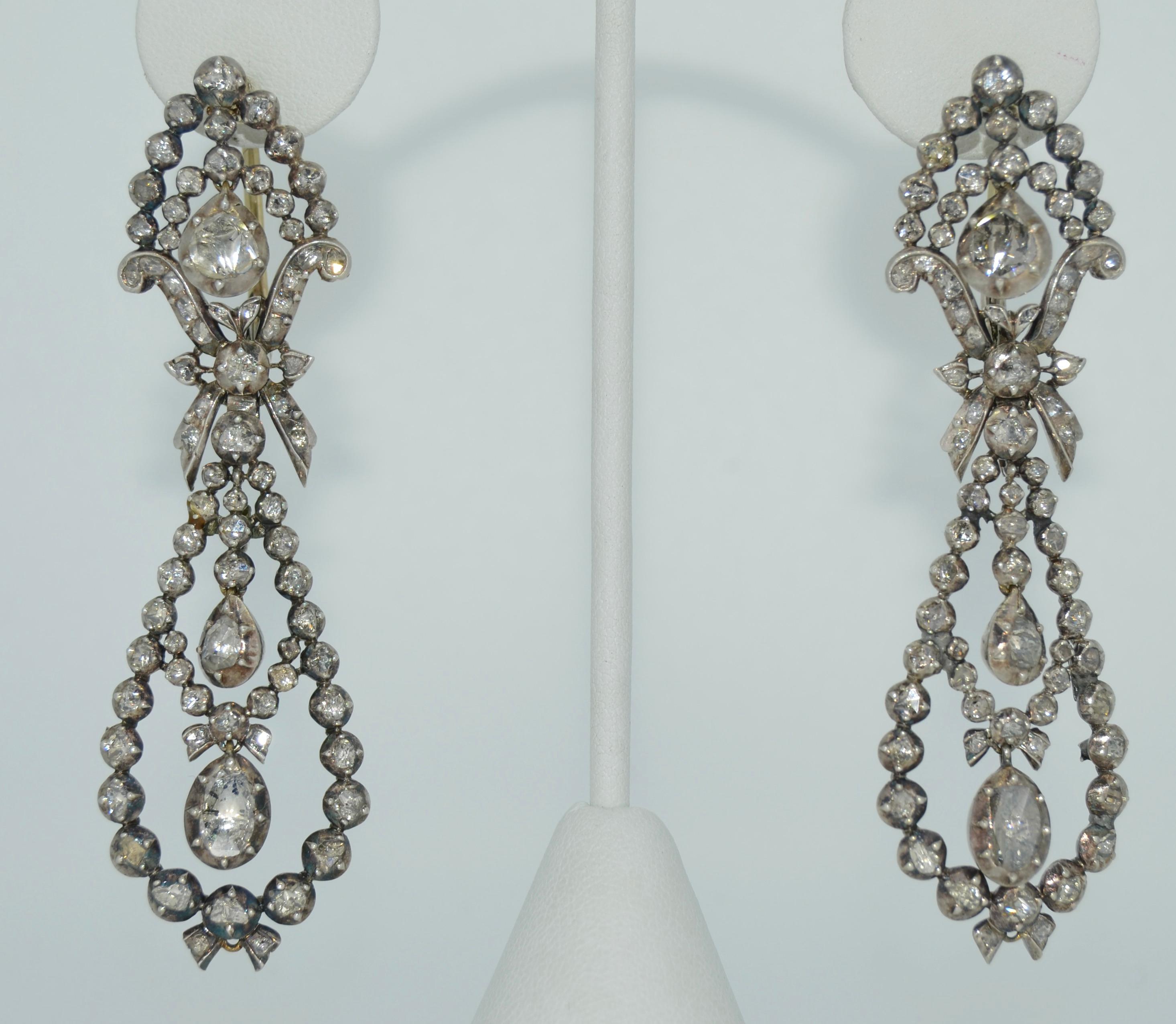 These are a spectacular pair of Georgian Era Pendant Day and Night Earrings. They are crafted from sterling silver with 14K ear wires. These earrings are covered in rose cut diamonds, all presented and accounted for. The top of the ear wires are
