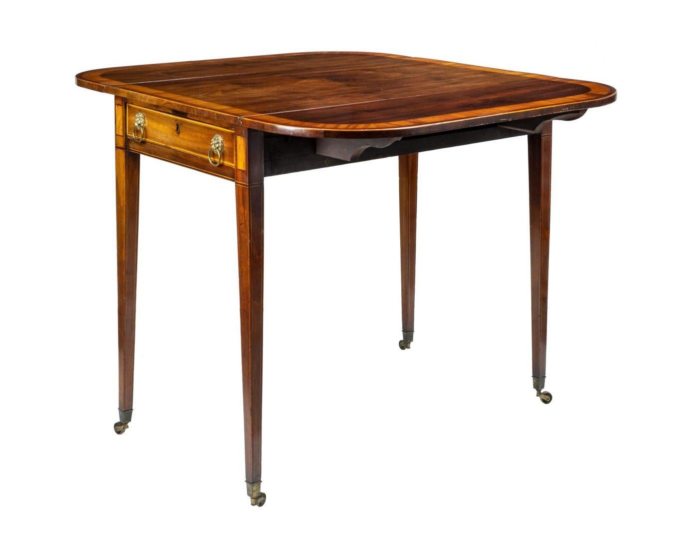 Georgian figured mahogany and satinwood cross-banded pembroke table, the rounded oblong top above a frieze drawer fitted with brass lion mask captive ring handles, and raised
on boxwood line inlaid square, tapering legs with brass