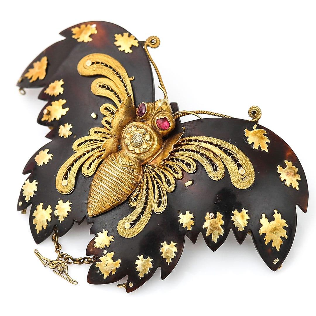 A fabulous Georgian gold filigree and cannetille detailed pique butterfly brooch adorned with ruby eyes dating from circa 1830. The wonderful early 19th century brooch has a highly detailed and hand formed gold body a top two round, faceted ruby