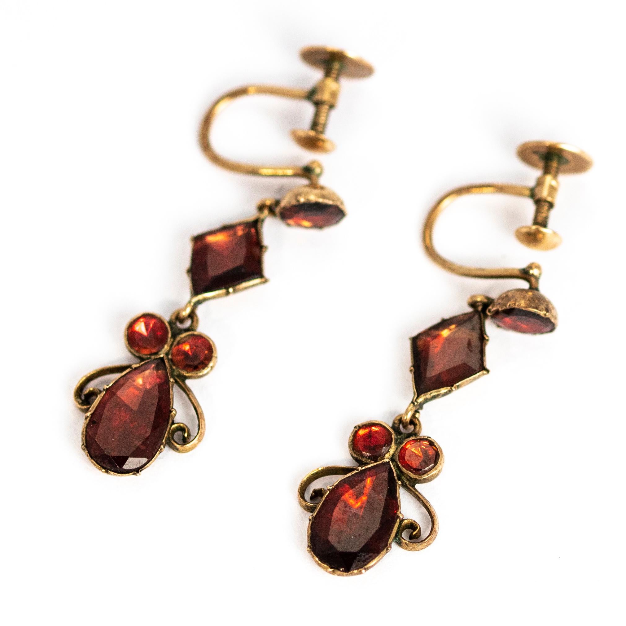 These stunning flat cut garnet and gold earrings are worn using a screw back and are very comfortable to wear. The drop part of the earring features some scroll detail and all the stones have a wonderful sheen to them.

Drop Length: 29mm 