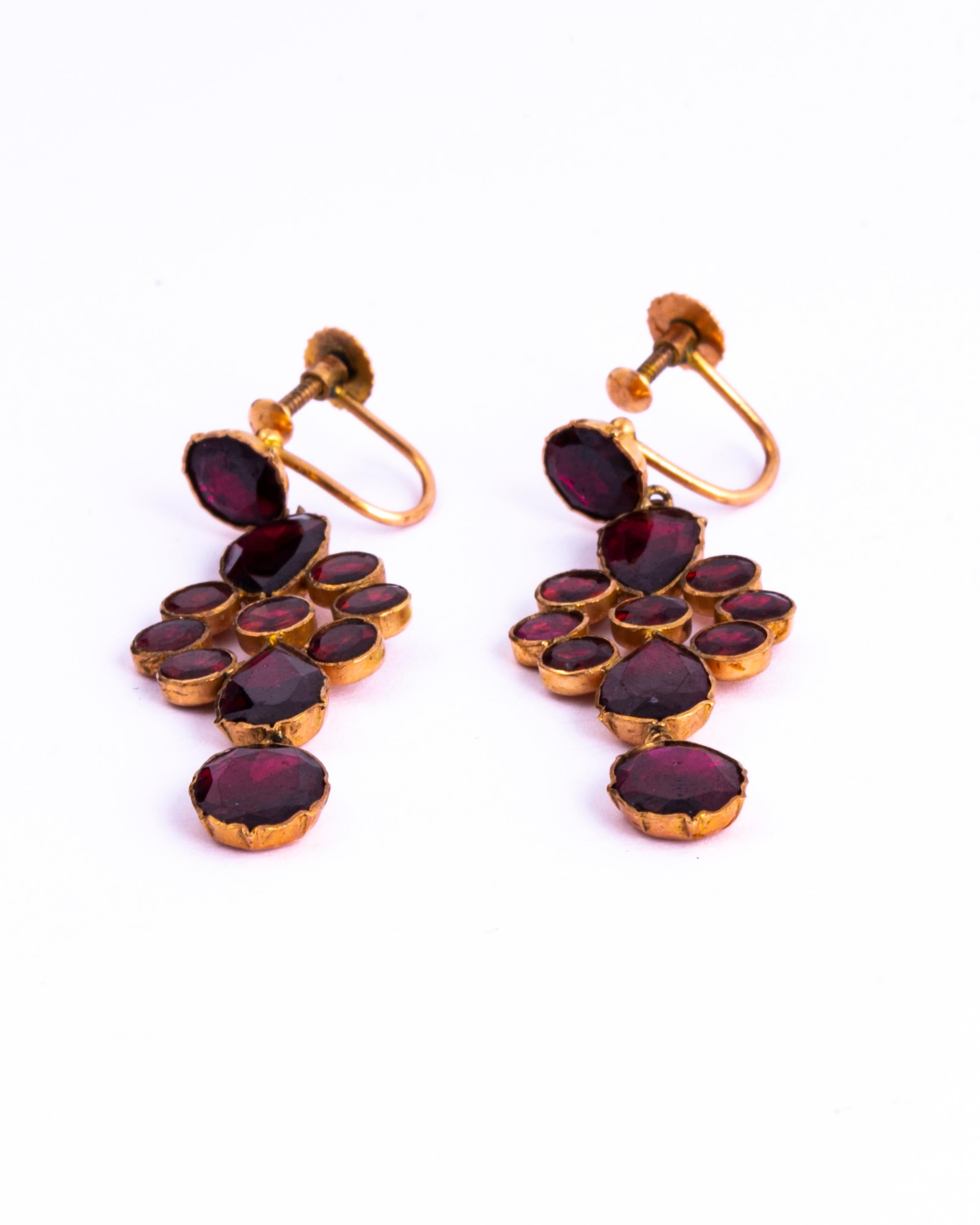 These stunning flat cut garnet and gold earrings are worn using a screw back and are very comfortable to wear. The earrings are made up of a round stone with a cluster with tear drops with a free hanging oval stone at the bottom.

Drop Length: 45mm