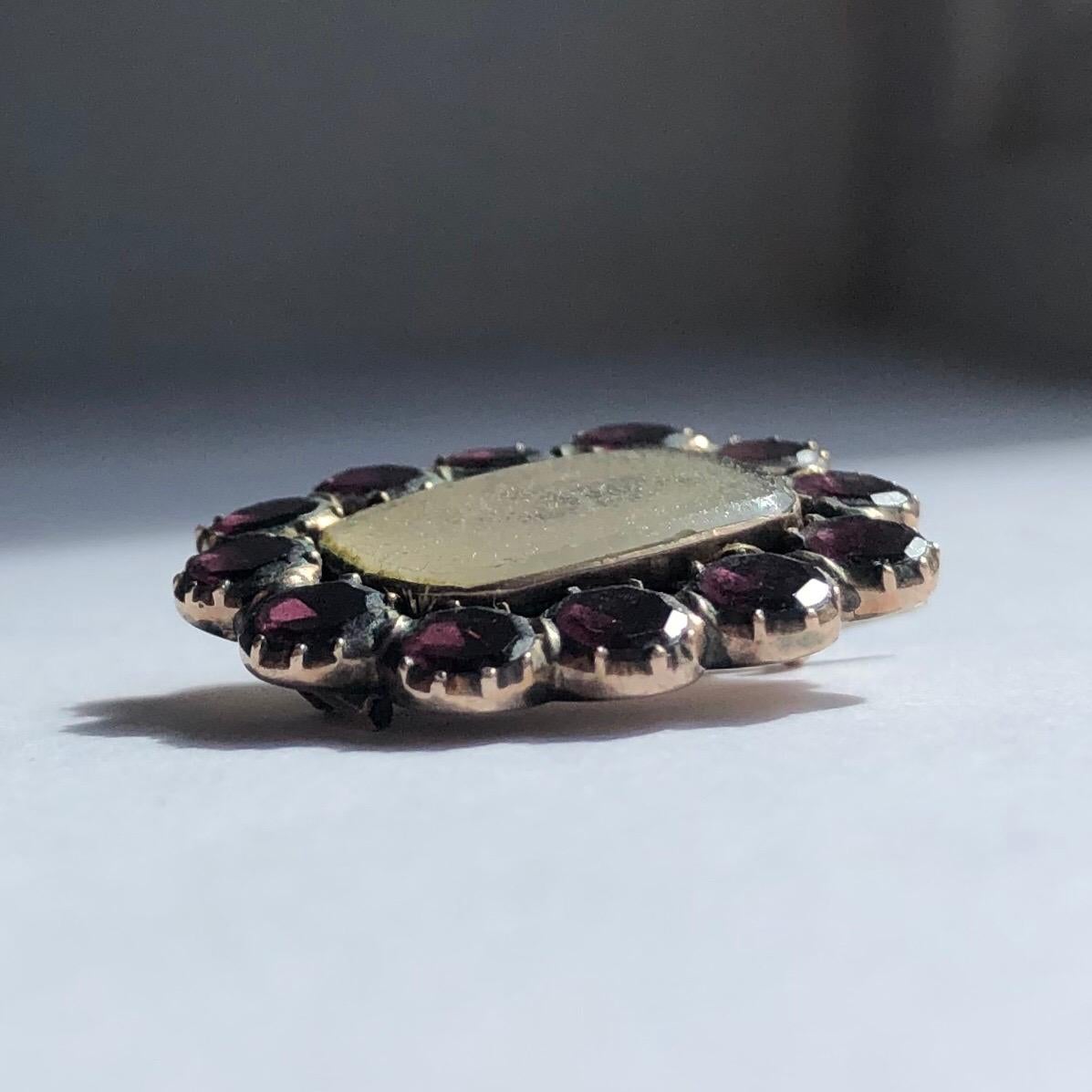 This stunning brooch would also make a stunning pendant! The hair behind the locket front is surrounded by beautiful flat cut garnets, typical of the Georgian period. 

Brooch Dimensions: 22x19mm

Weight: 2.58g
